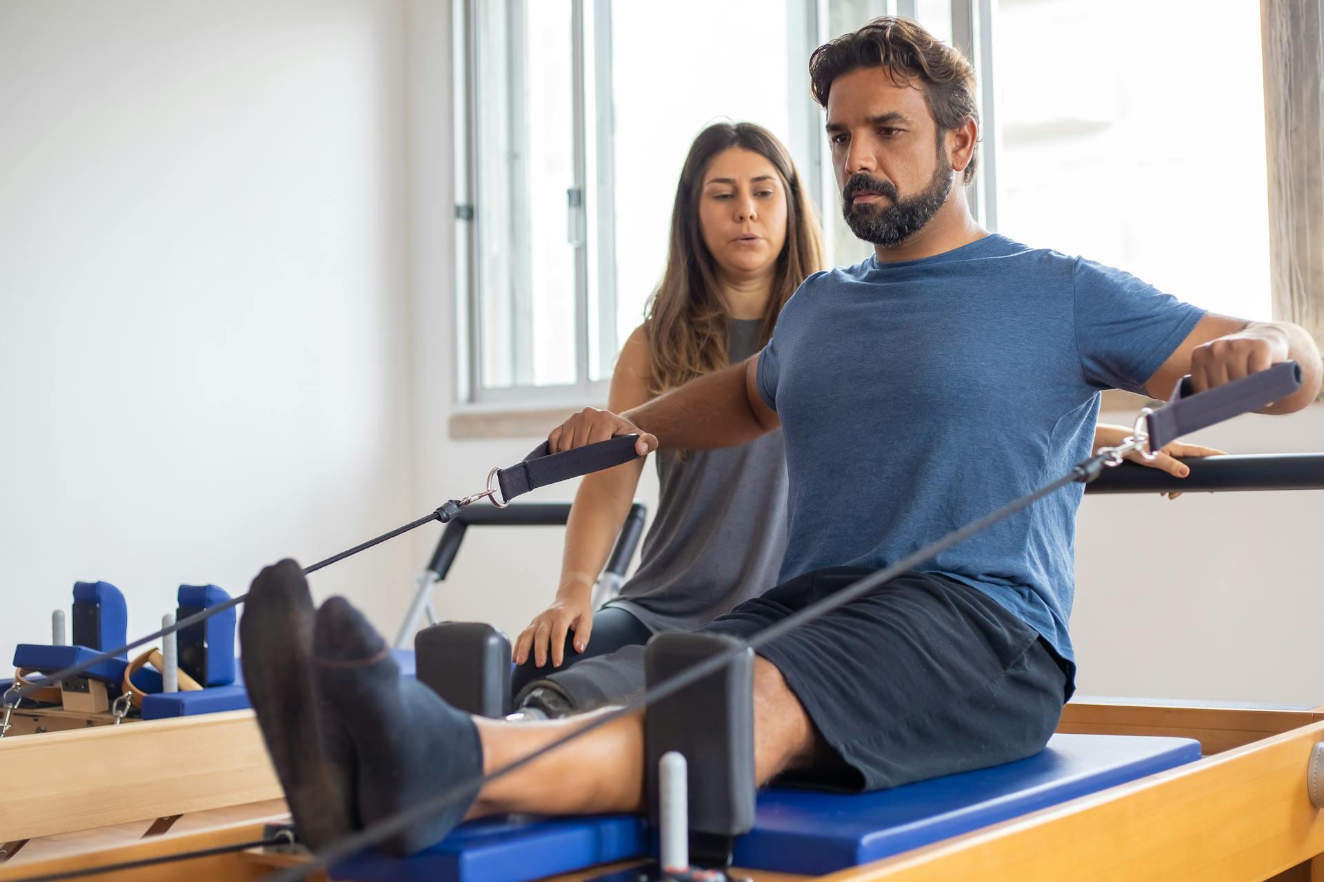 Mies harjoittelemassa pilates-laitteella