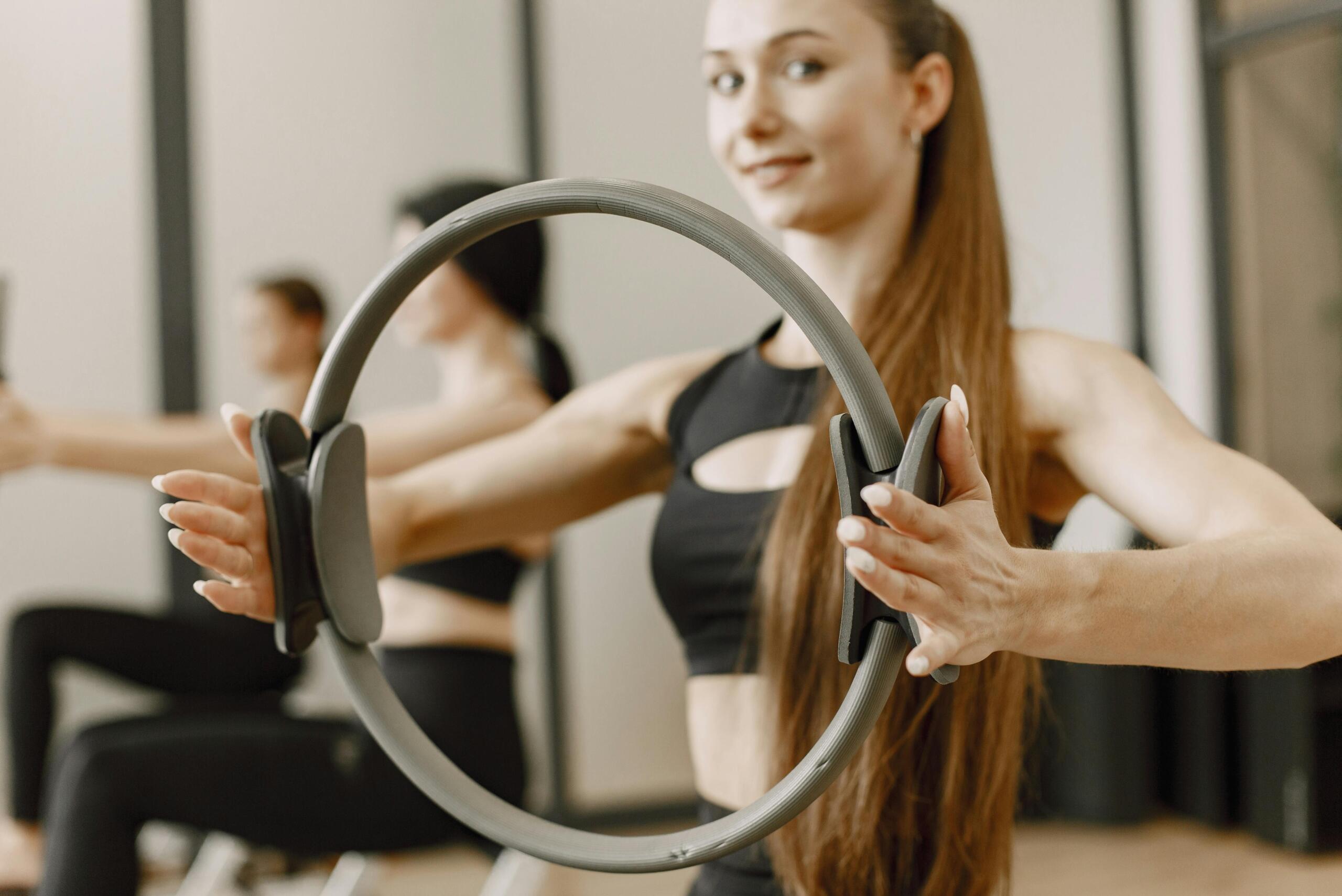 Nainen pitelemässä pilates-rengasta käsiensä välissä