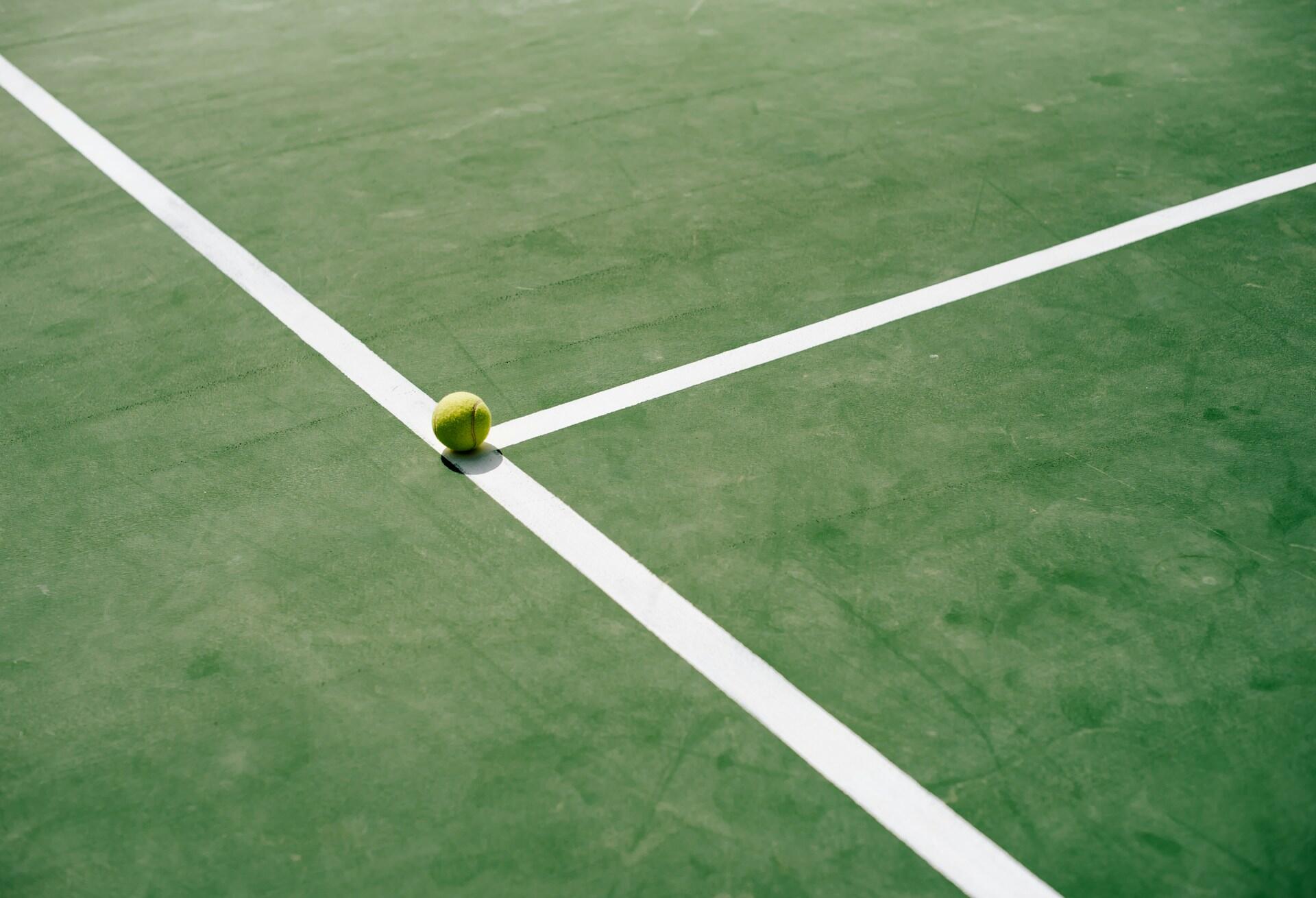 Keltainen tennispallo valkoisella viivalla
