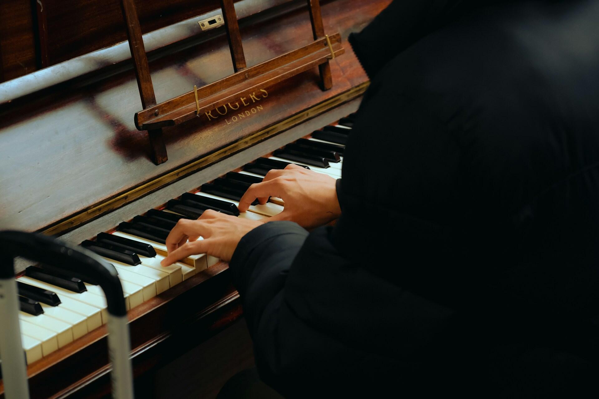 Henkilö soittamassa akustista pianoa