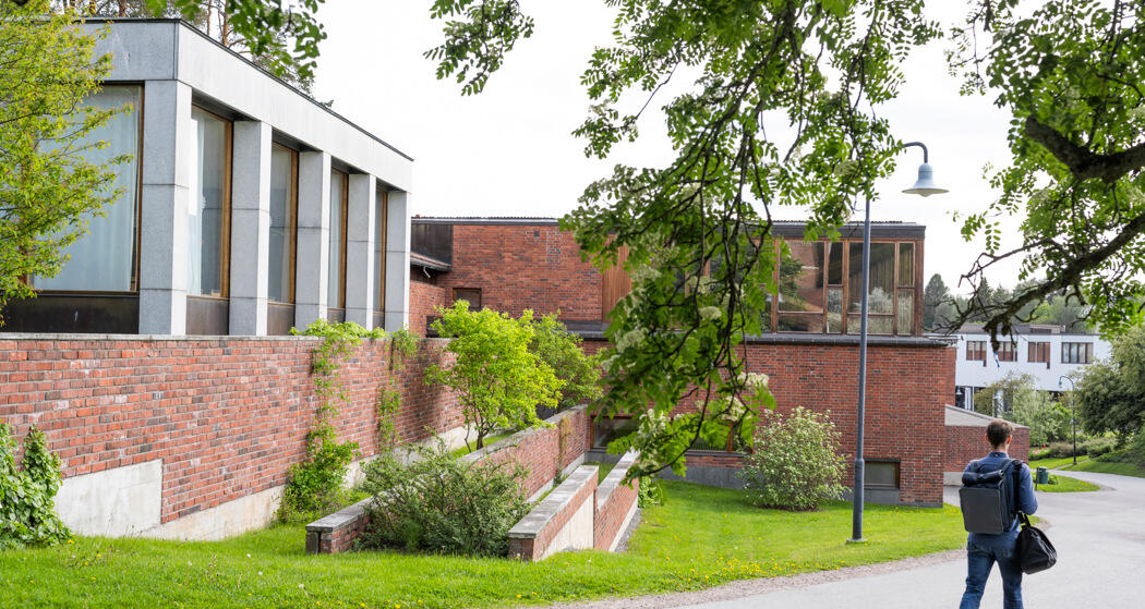 Henkilö kävelemässä punaisen rakennuksen rinnalla