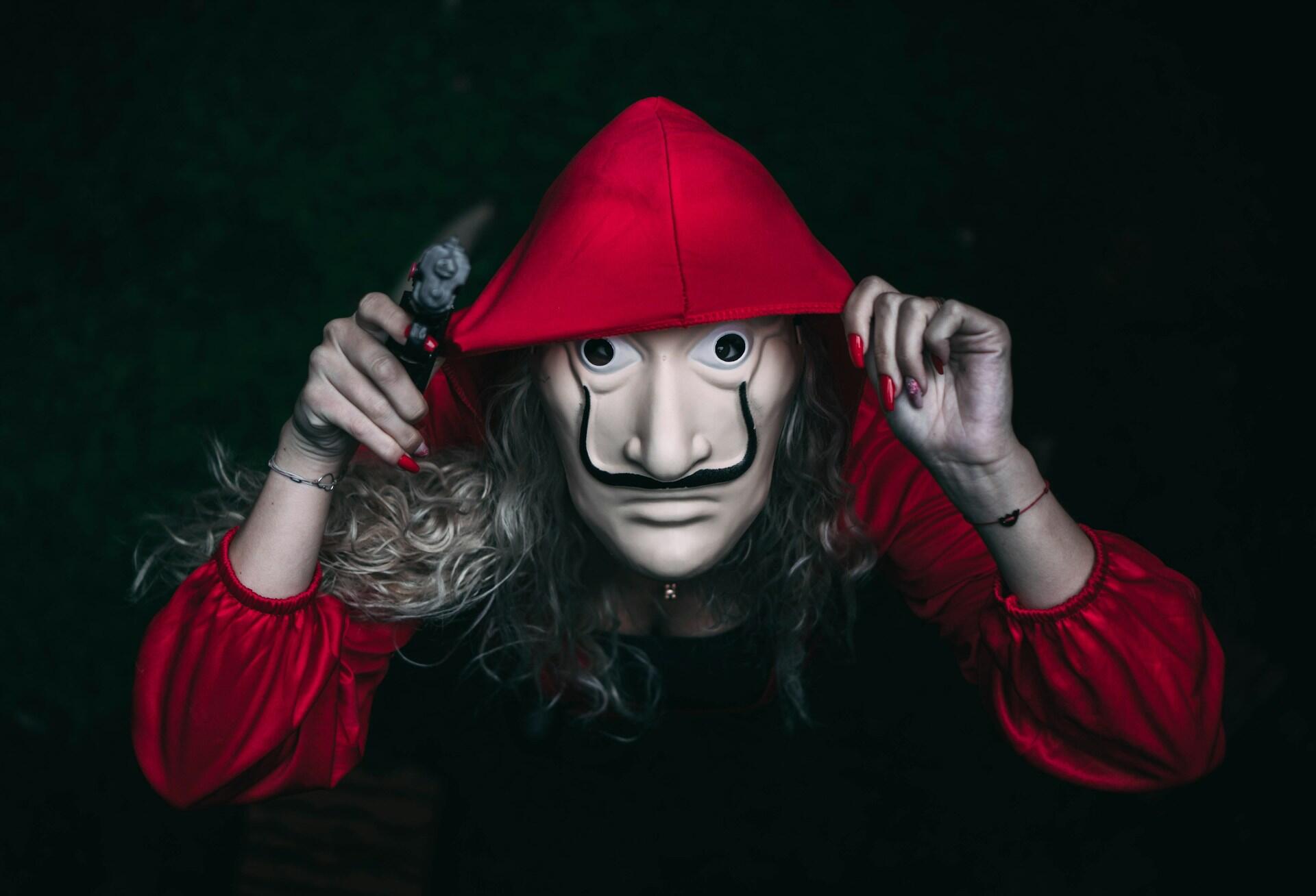 Henkilö maski kasvoilla punainen huppu päässä