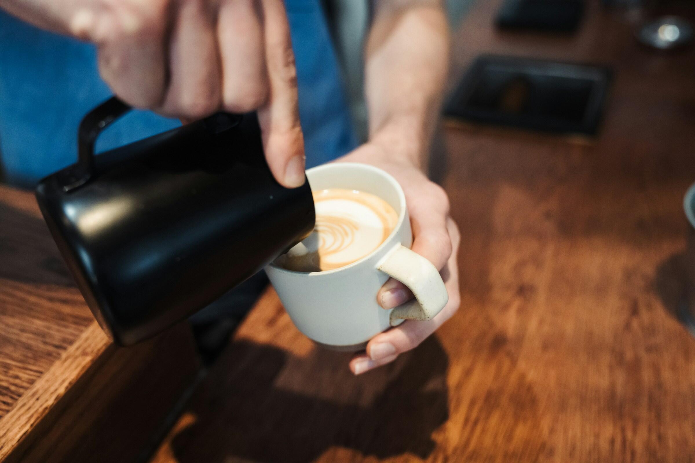 Maidon kaataminen kahviin mustasta maitokannusta