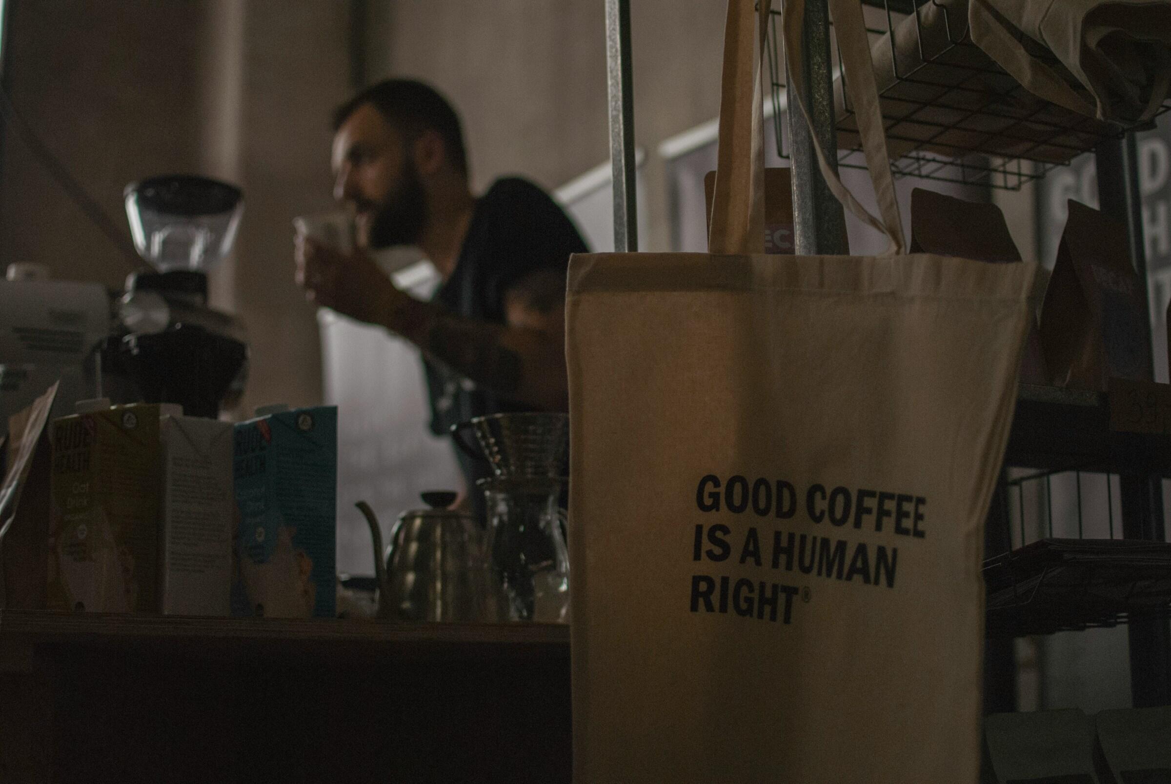 Kahviin liittyvä kangaskassi ja barista taustalla