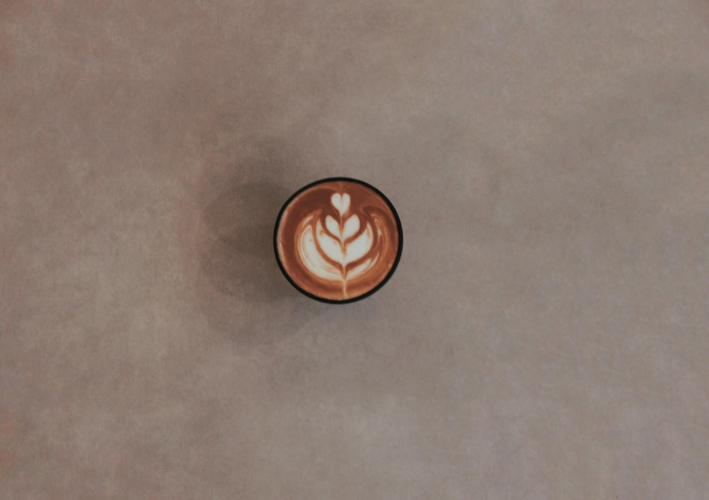 Kahvikuppi espressolla ja latte artilla beigellä asfalttilattialla