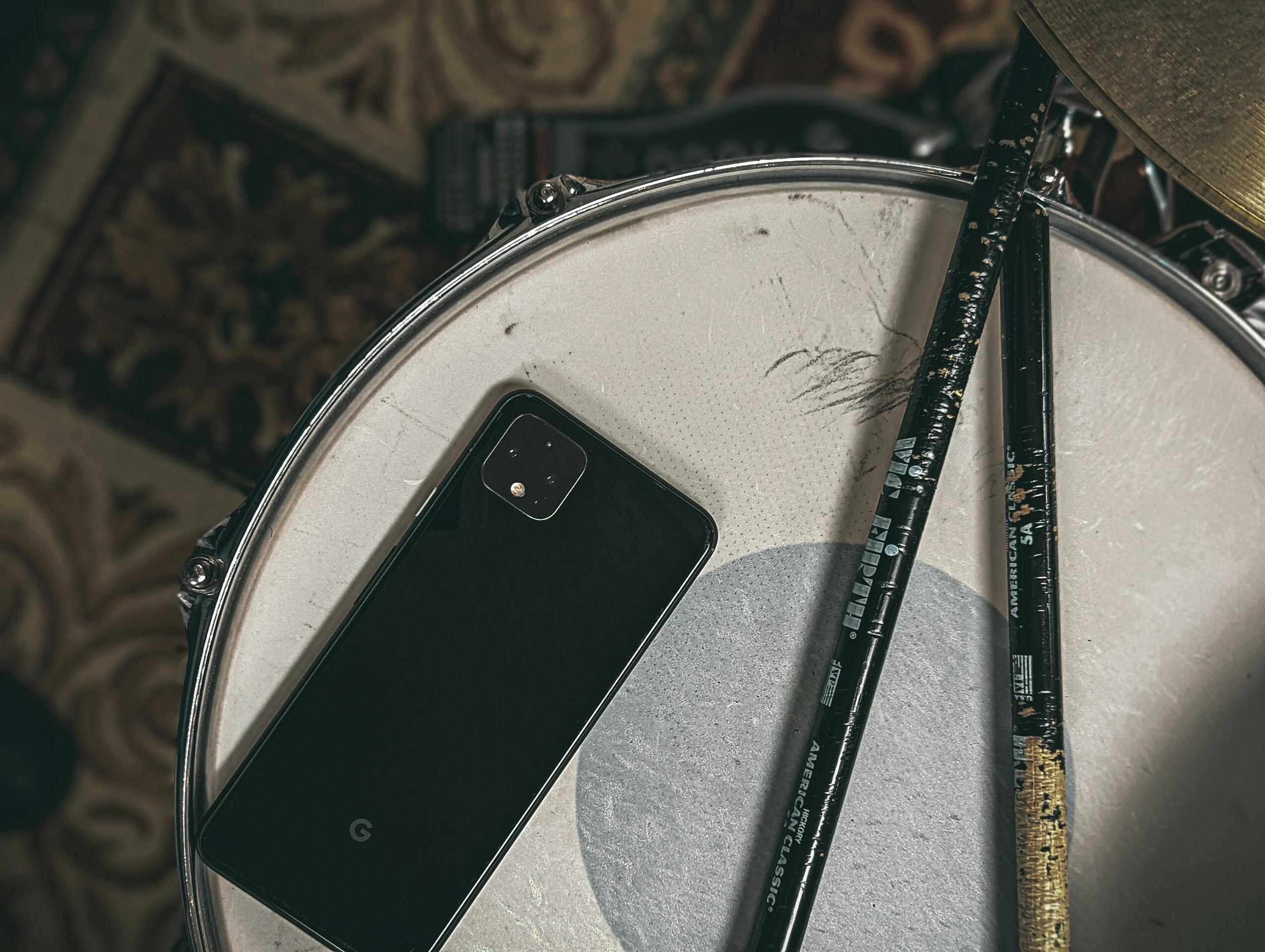 Puhelin ja rumpukapulat virvelirummun päällä