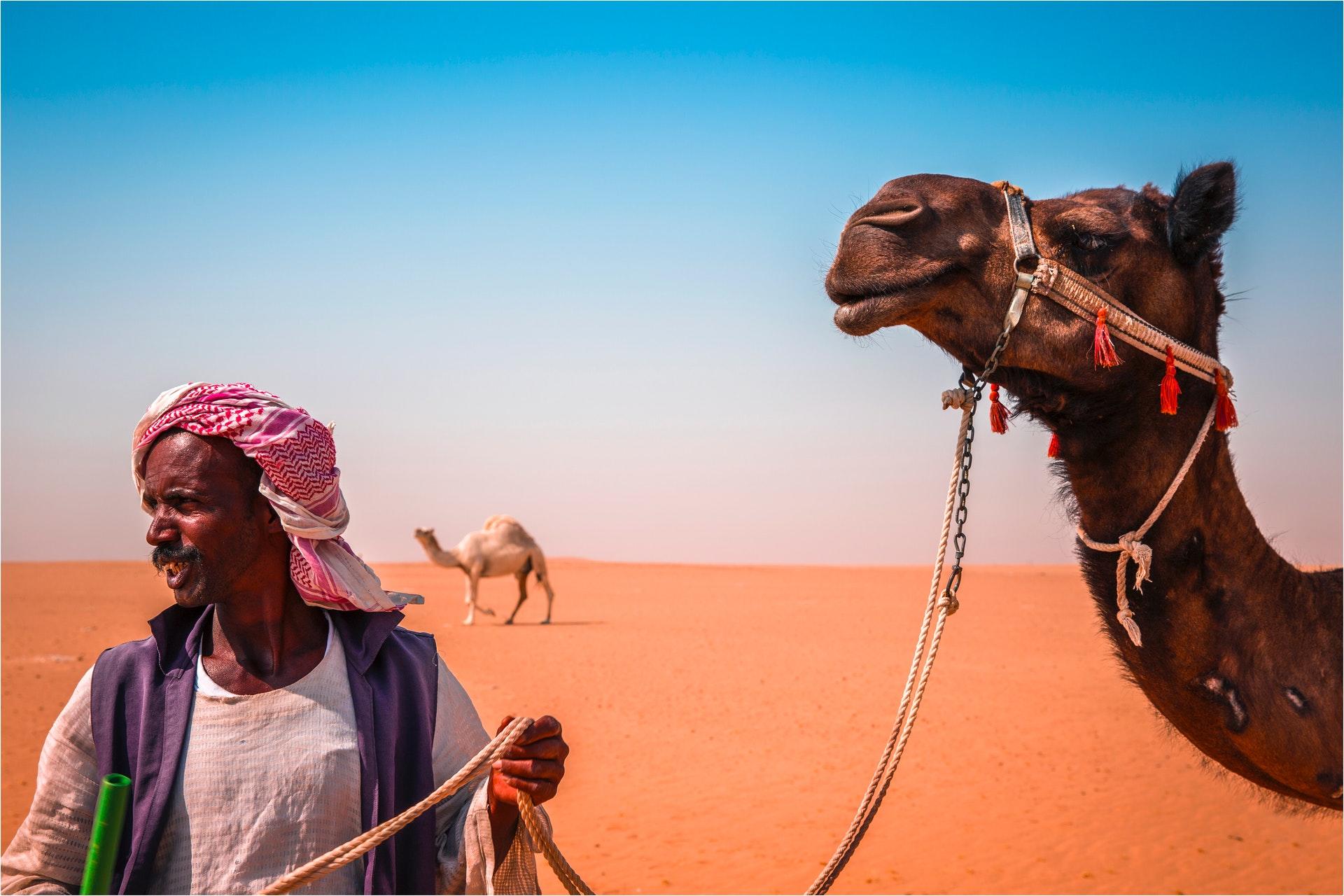 Arabische persoon met kameel in een woestijn