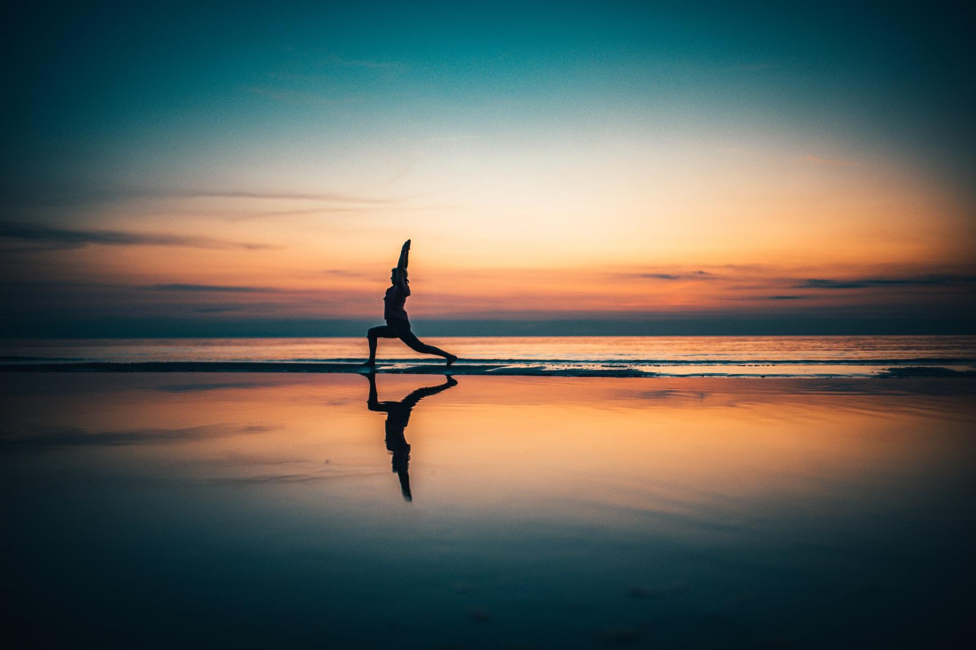 Persoon doet yoga op strand