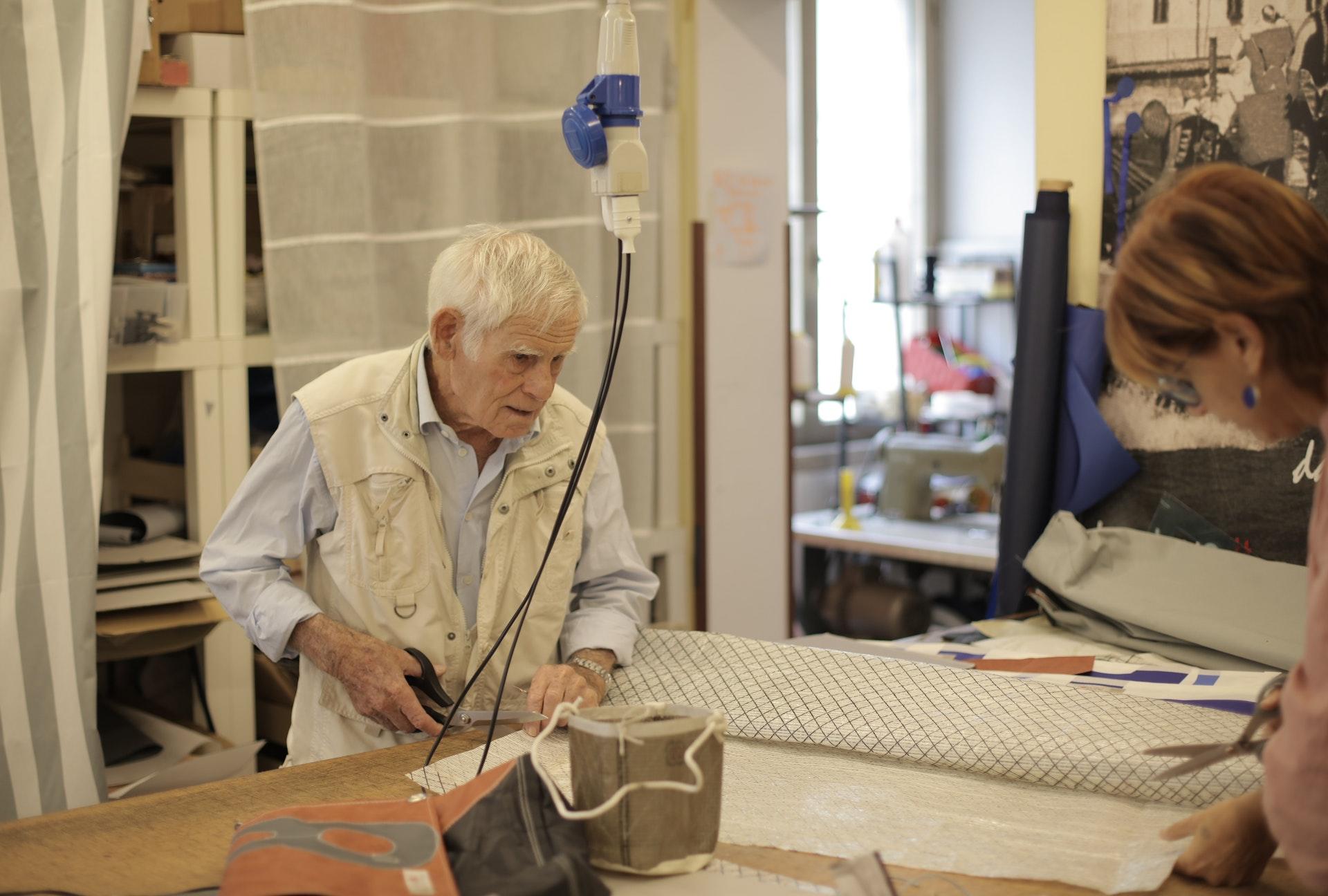 Ouder man leert naaien en knipt stoffen af