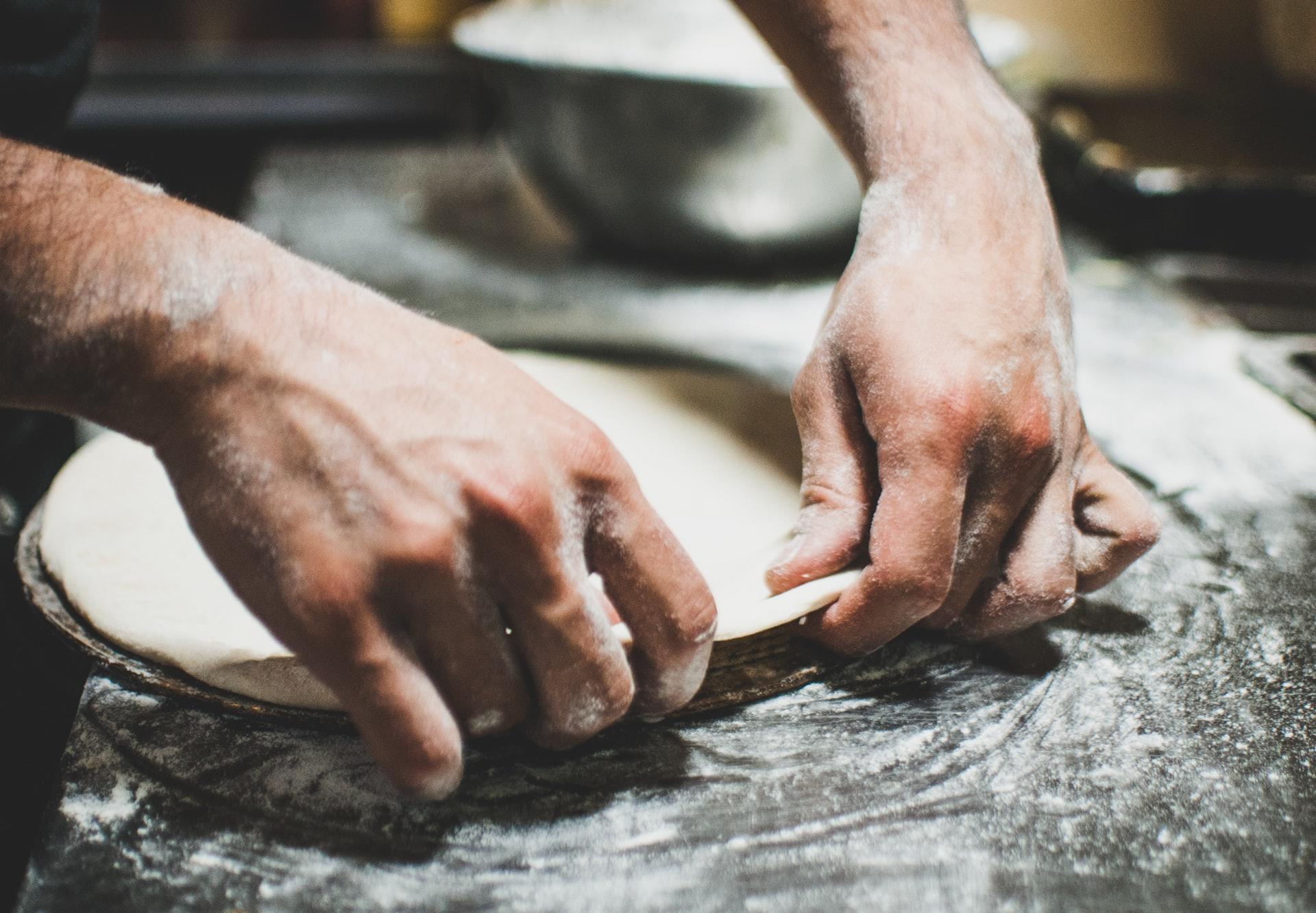 Man rolt pizzadeeg uit