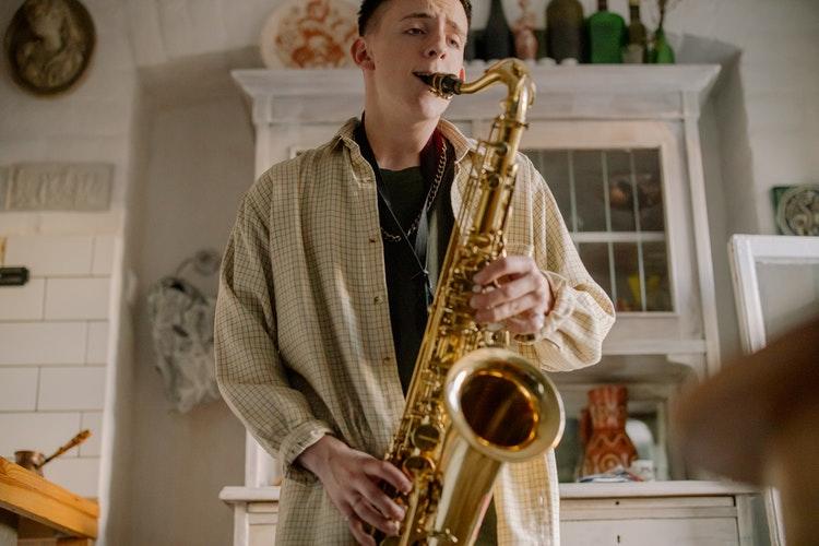 Jongen speel saxofoon in woonkamer 