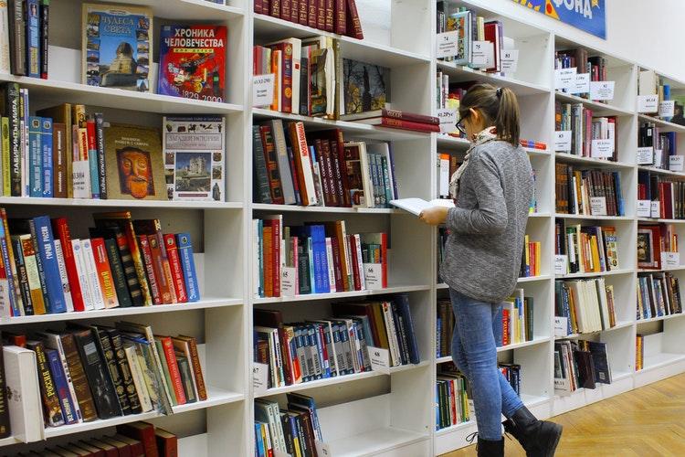 Vrouw zoekt naar boeken in bibliotheek