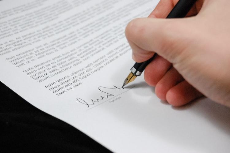 Notaris zet handtekening op papier