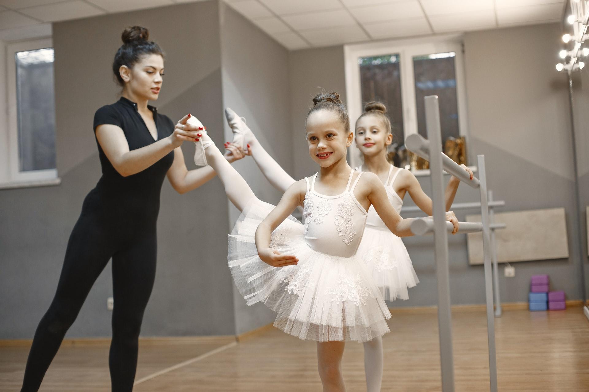 Ballet leerkracht helpt kinderen met balletpassen