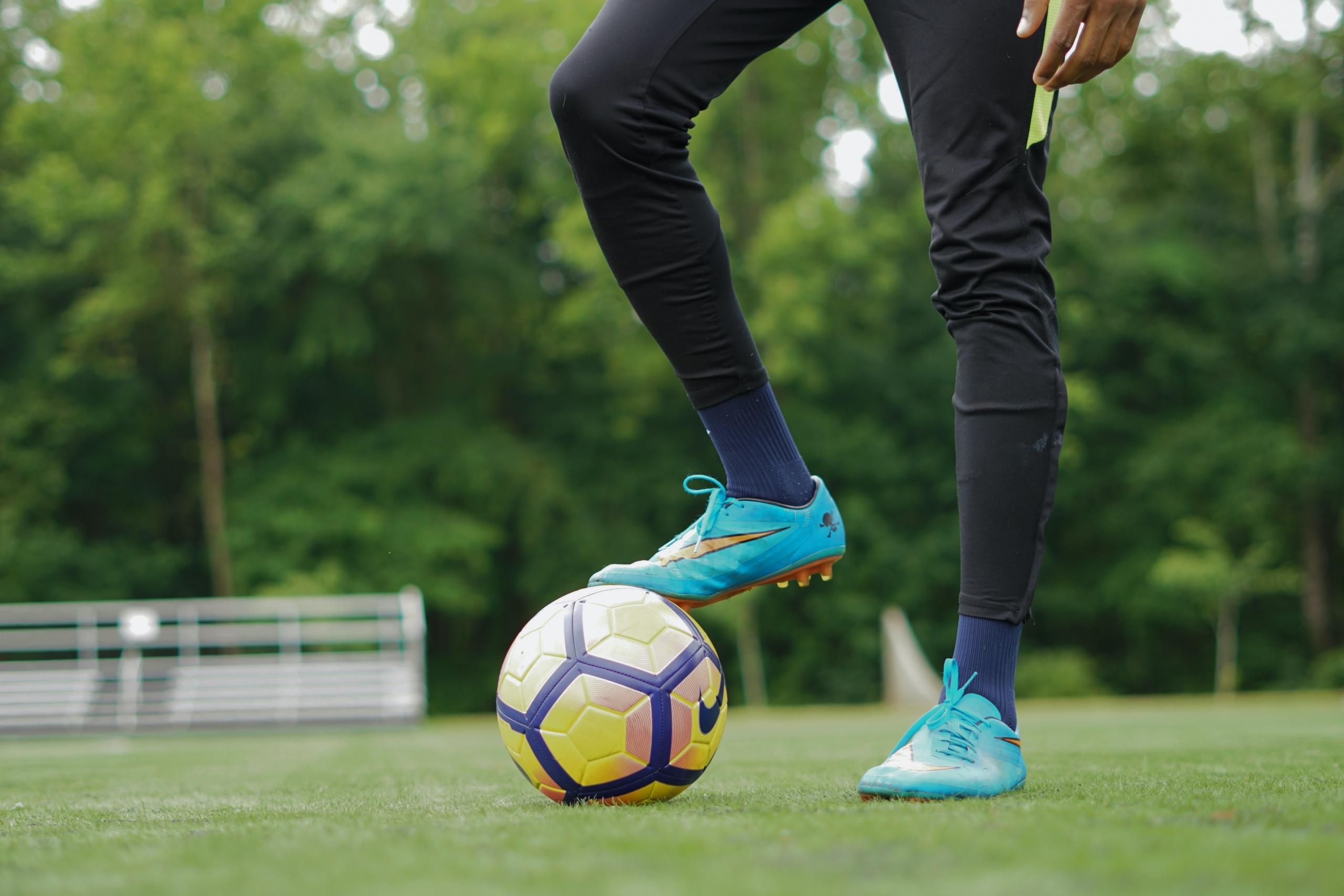 Voetballer staat met schoen op voetbal