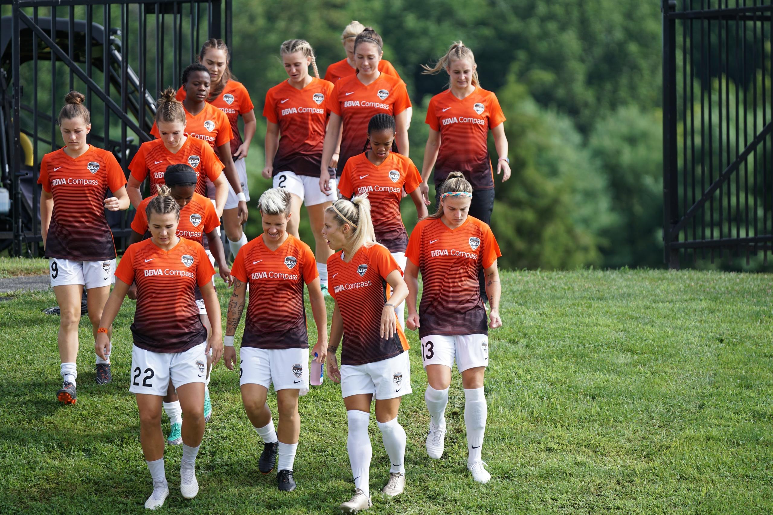 Vrouwen voetbal ploeg wandelt veld op.