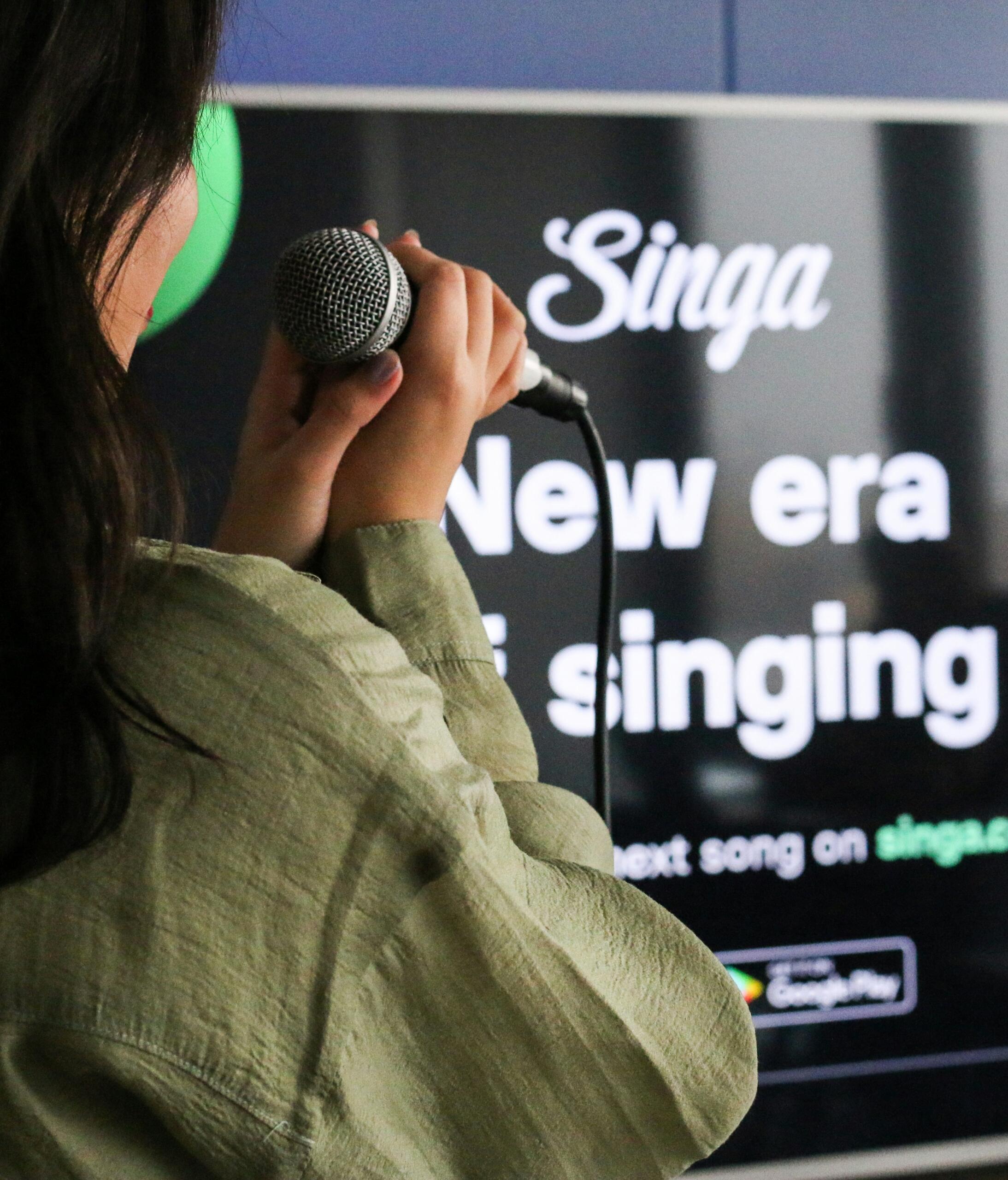 Persoon zingt karaoke met een microfoon | Bron: Singa Karaoke, via Unsplash