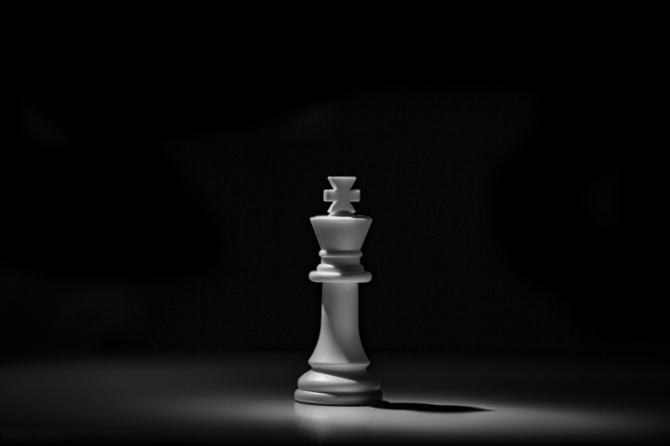 Witte schaakdame tegen een donkere achtergrond | Bron: Hassan Pasha, via Unsplash