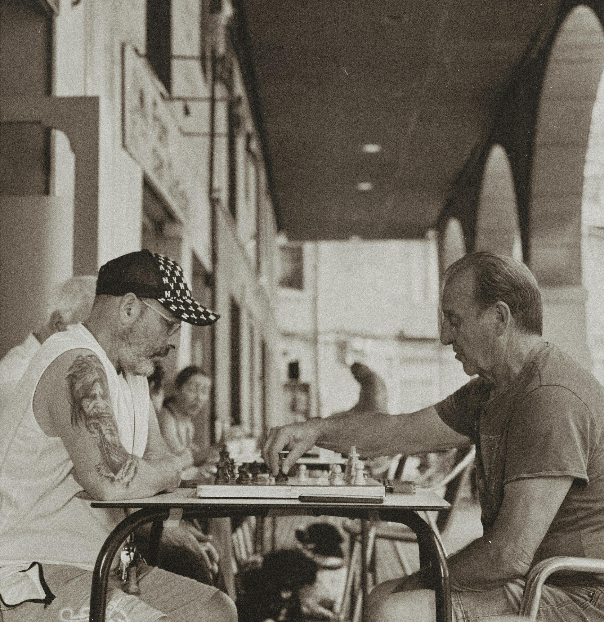 Twee mannen spelen samen een partij schaak op een terras | Bron: LA REB, via Unsplash
