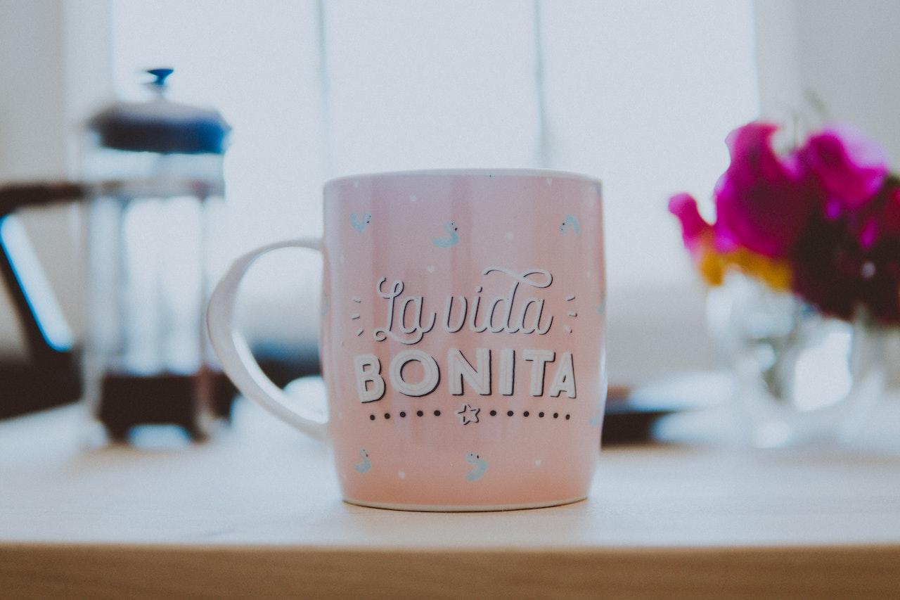 Tasse de café rose avec écrit dessus en espagnol 