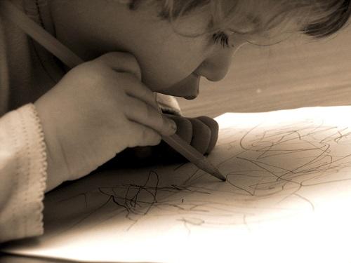 L'enfant s'entraîne à maîtriser ses gestes en tenant un crayon.
