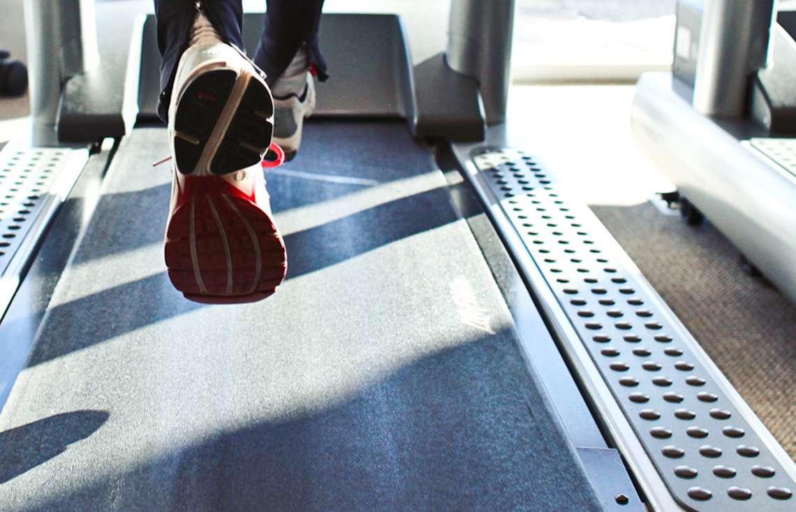 Une personne qui court sur un tapis de course en baskets. 