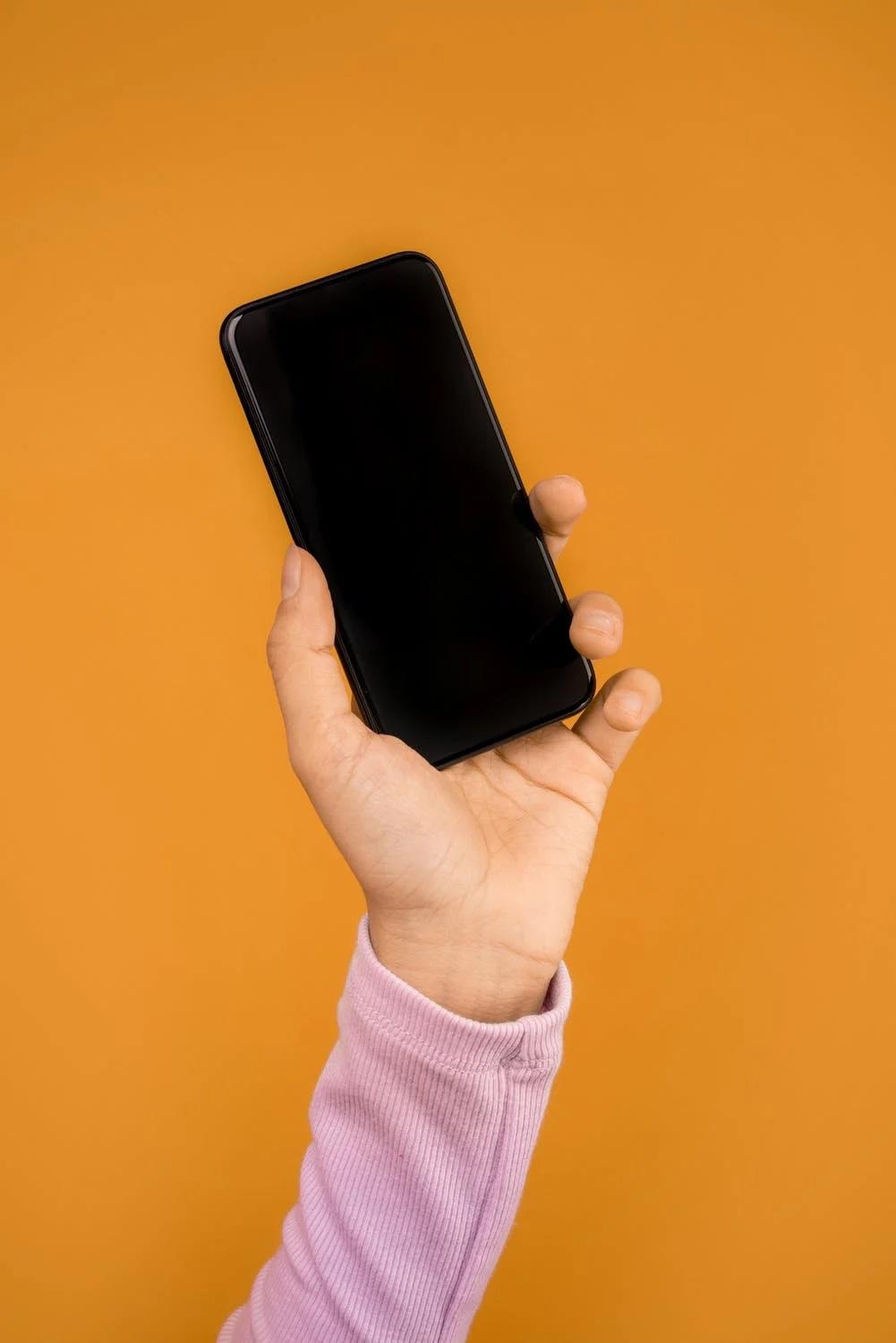 Une main tient un smartphone.