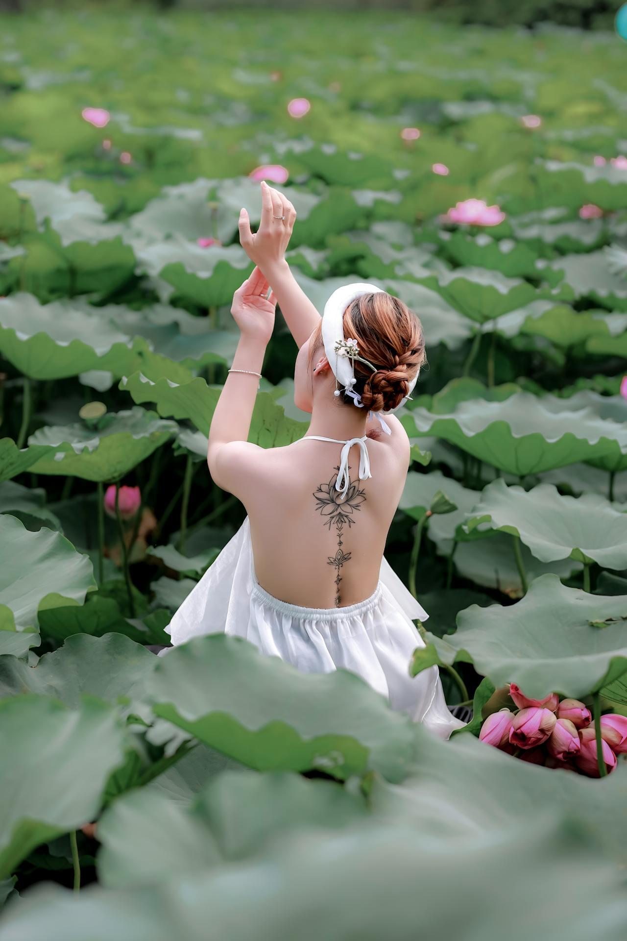 Tatouage chinois d'une fleur de lotus dans le dos d'une jeune femme assise. 