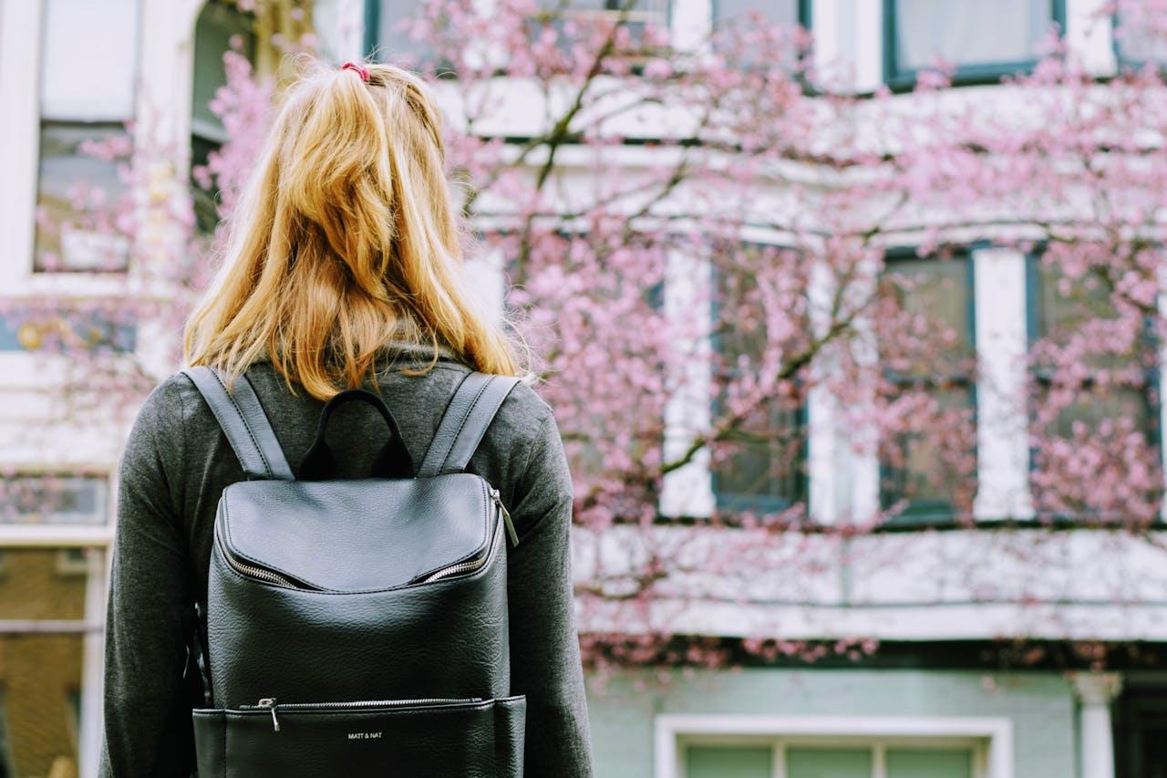 Jeune fille de dos devant des cerisiers en fleur.