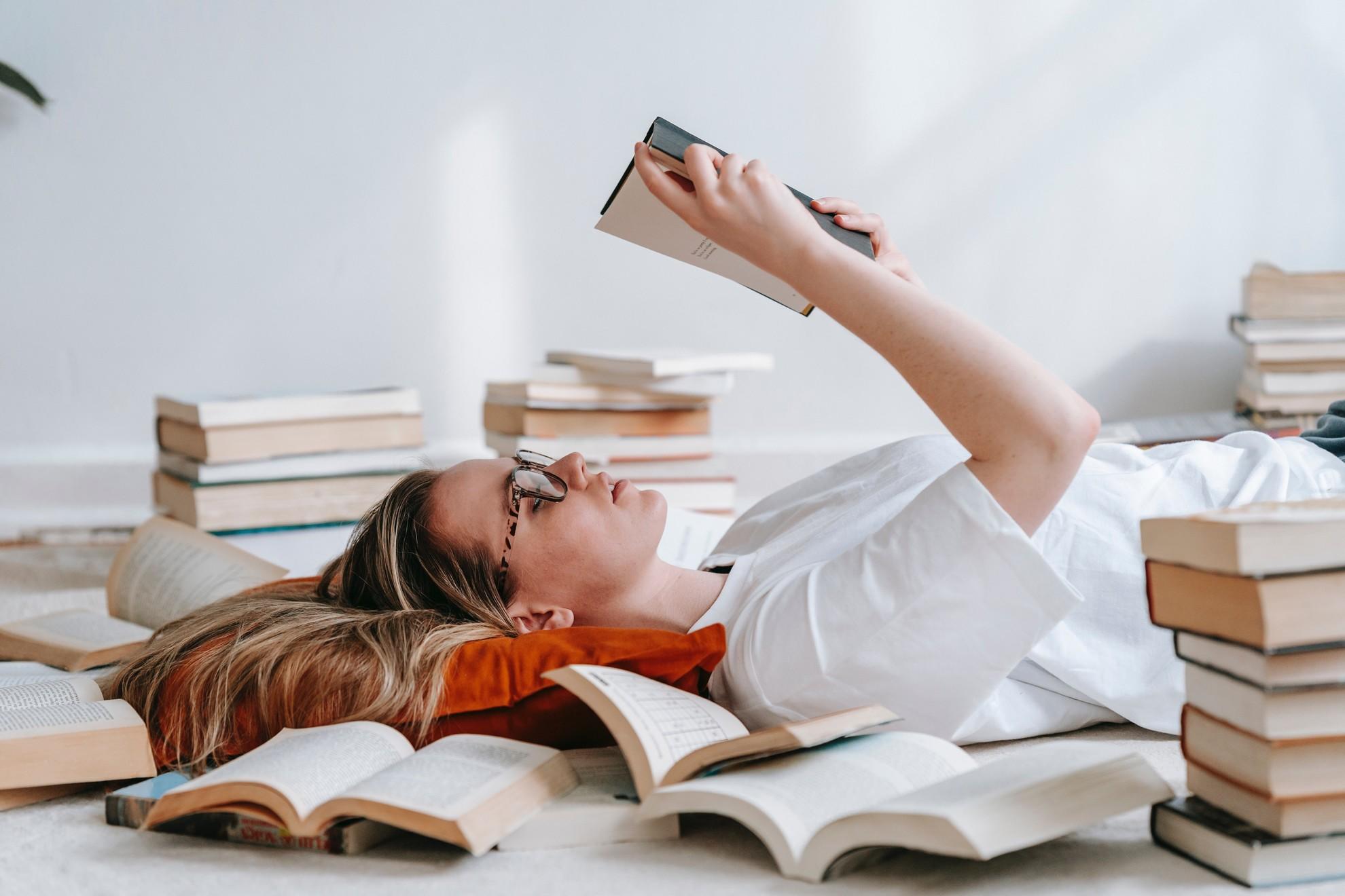 Une personne en train de lire une pile de livres.