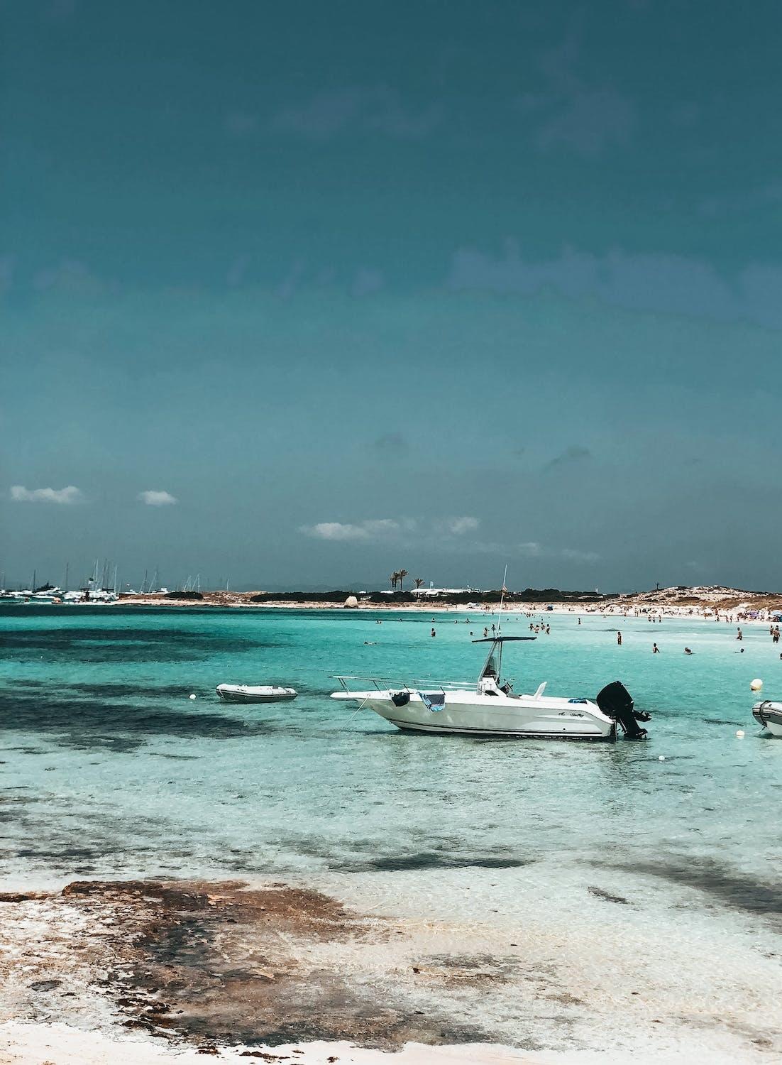 Plage paradisiaque avec des bateaux et des personnes qui se baignent.