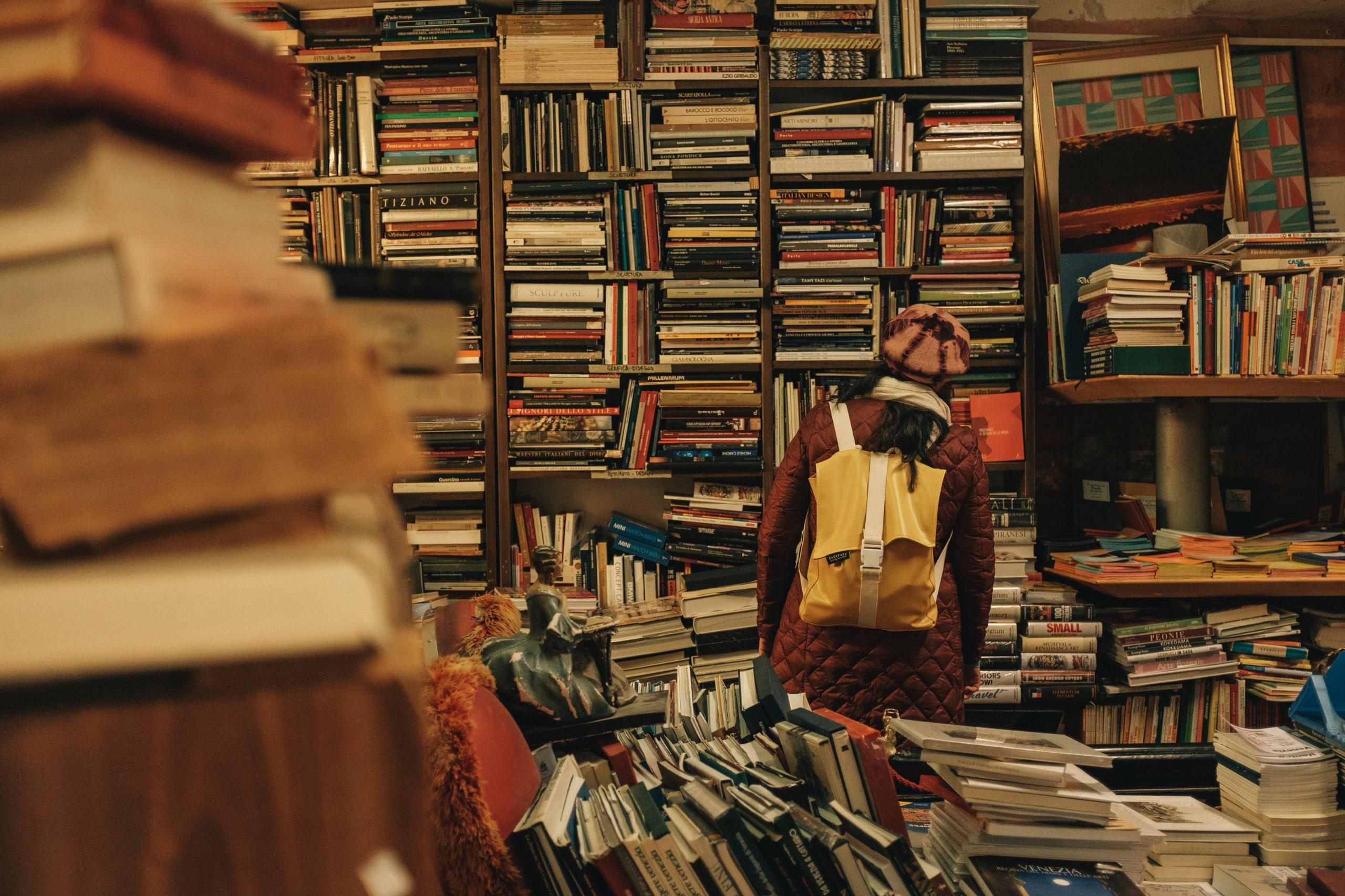 Une fille de dos cherche une livre dans une librairie.