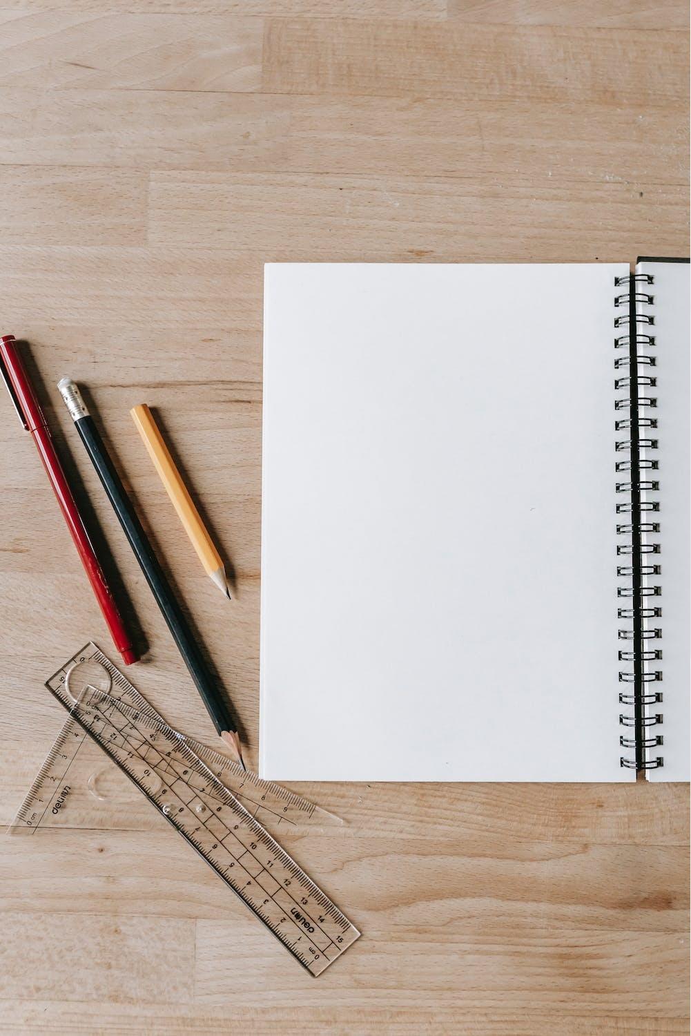 Un cahier, des crayons et règles sont posés sur la table.