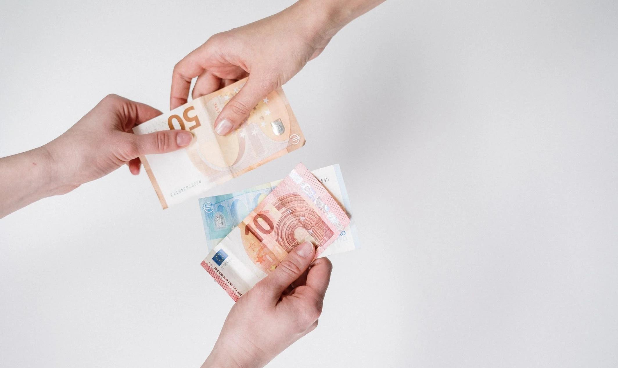 Des mains échangent des billets en euros.