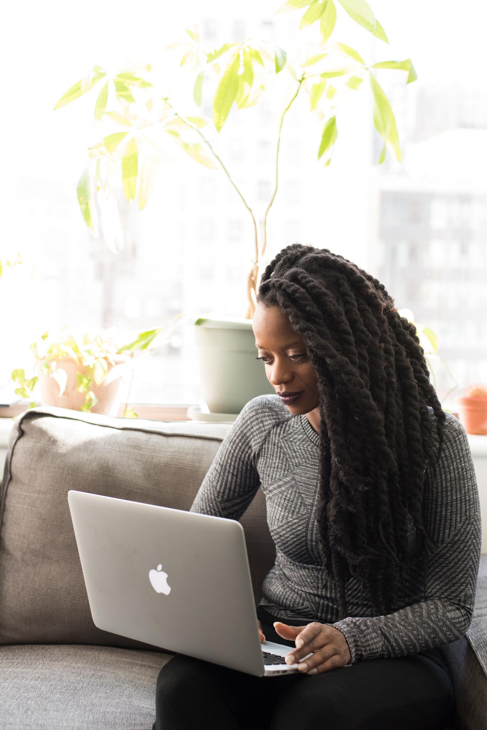 Une femme écrit un texte sur son Mac.