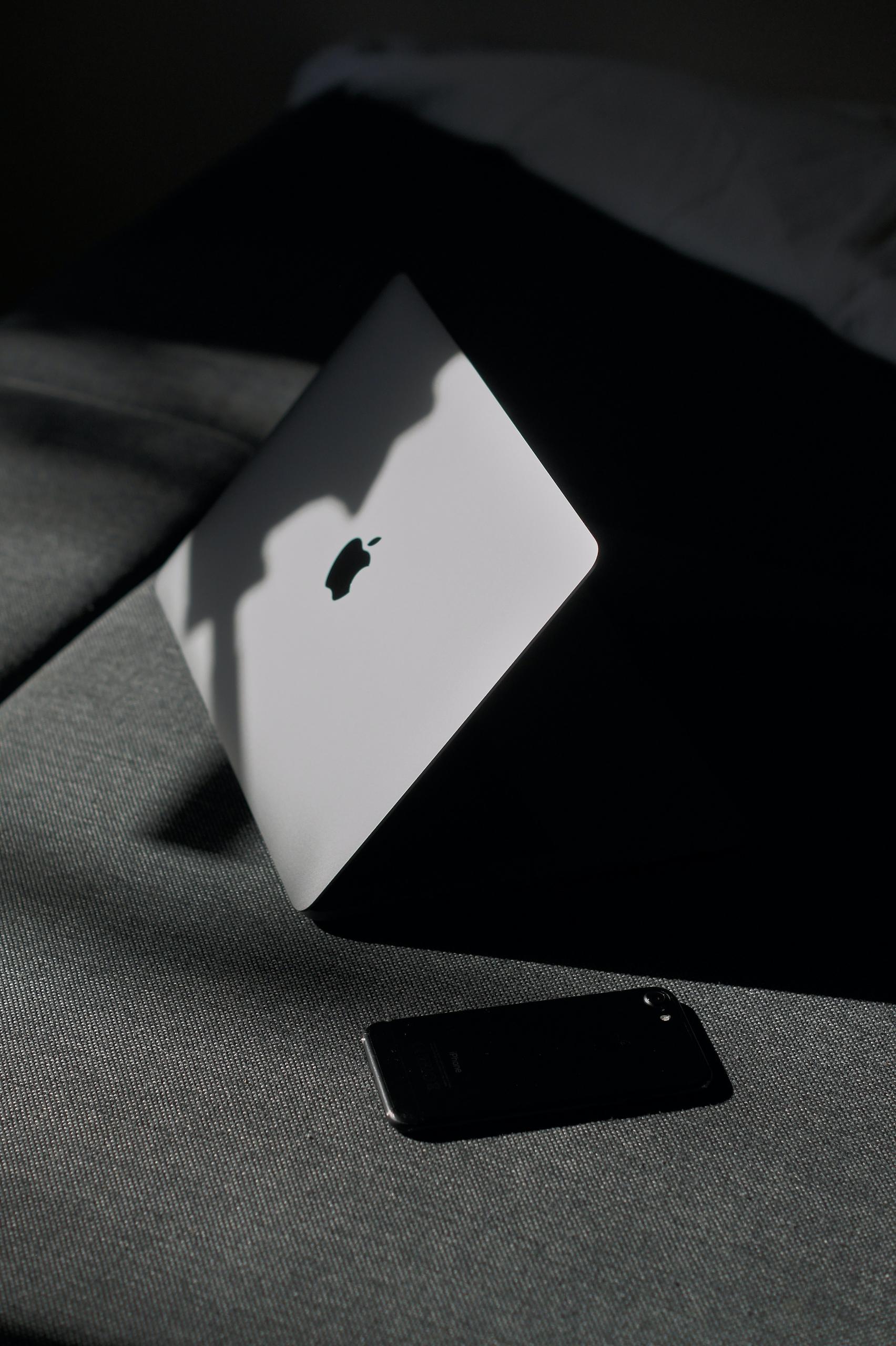 Un mac posé sur un canapé éclairé par le soleil.