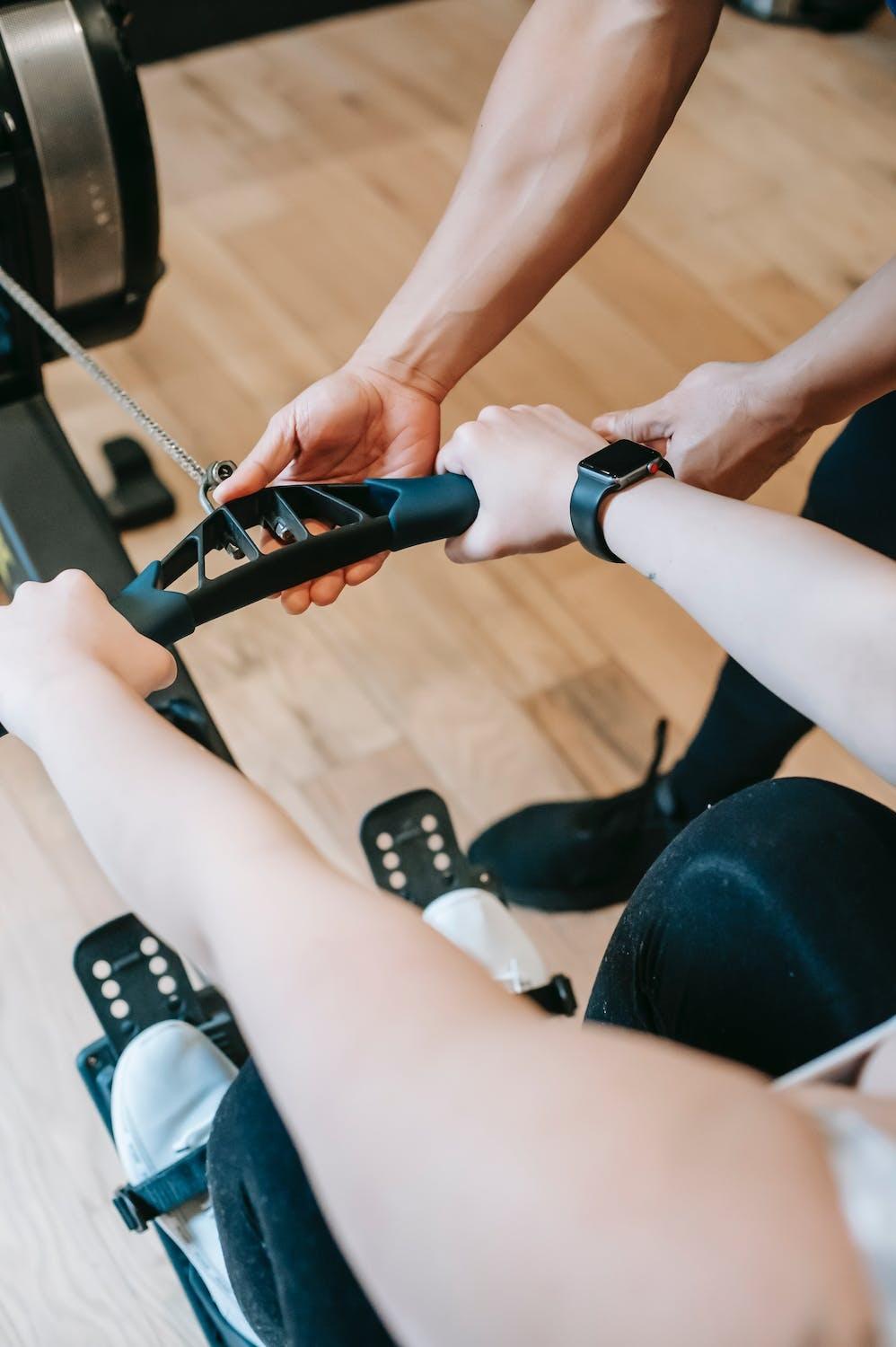 Une personne apprend à utiliser un rameur avec un coach sportif.