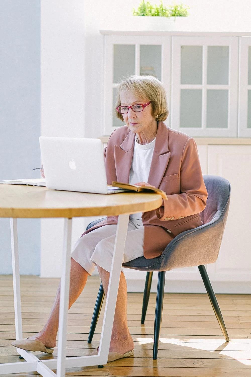 Une senior utilise un ordinateur sur une table.