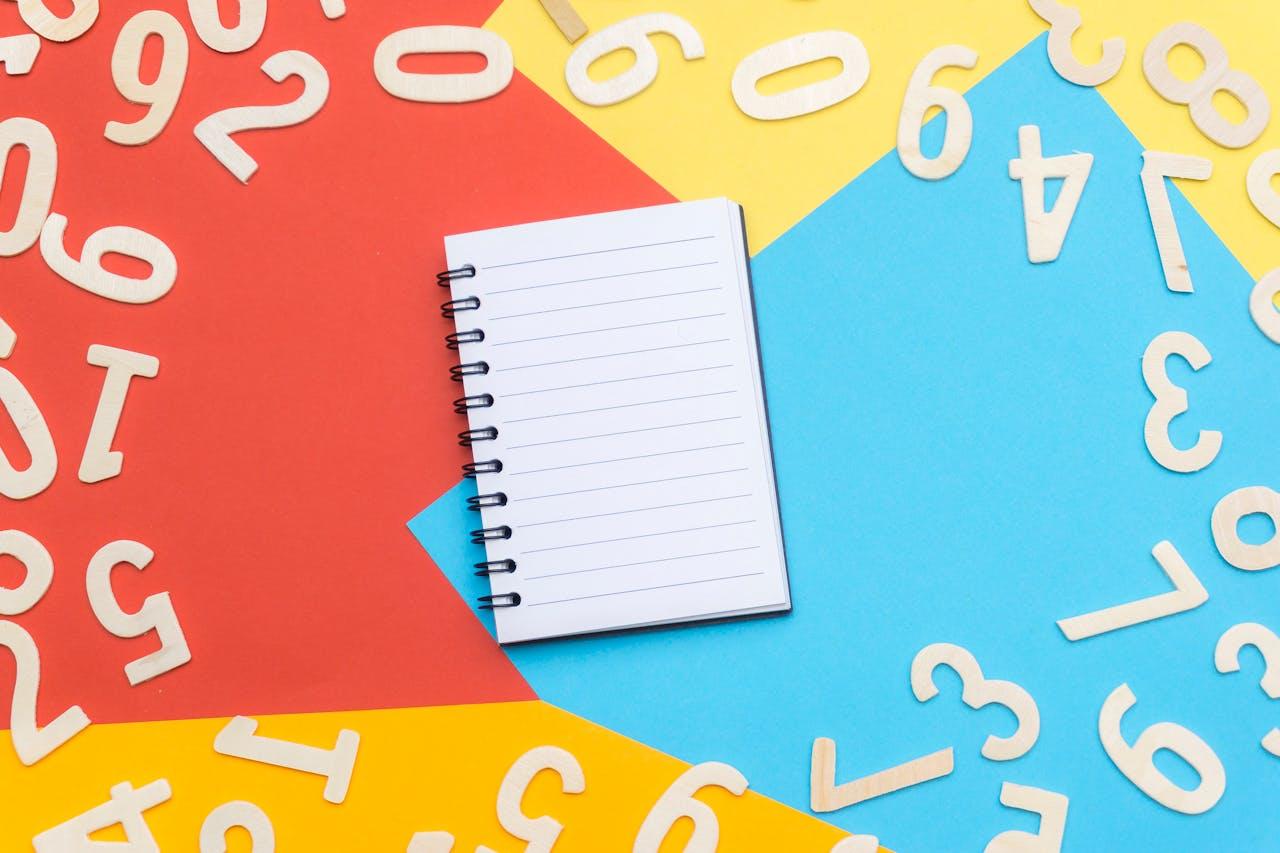 Chiffres étalés sur un fond de couleur rouge, bleu et jaune avec un carnet posé au milieu.