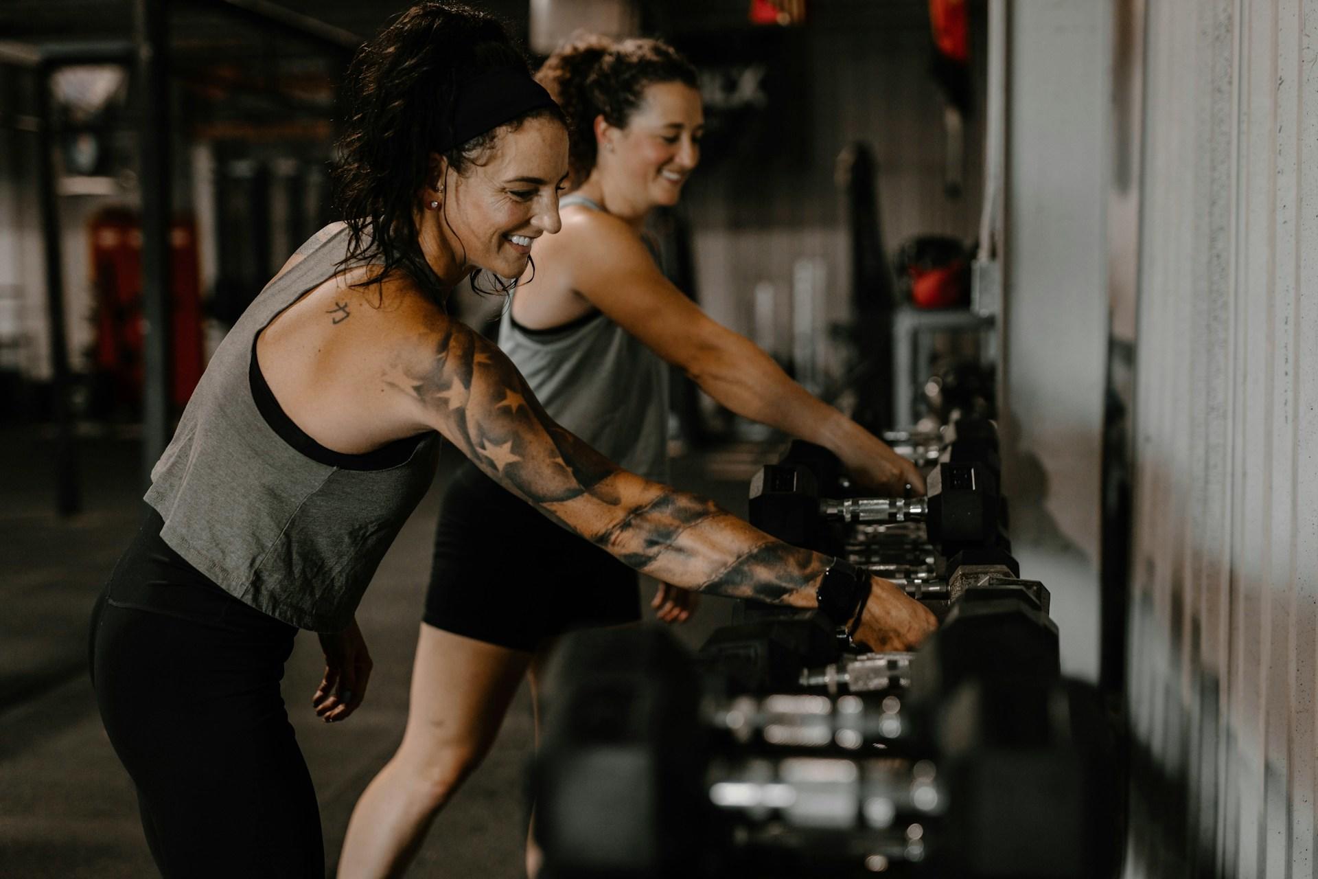 deux femmes en train de choisir des poids pour un entrainement en salle de sport