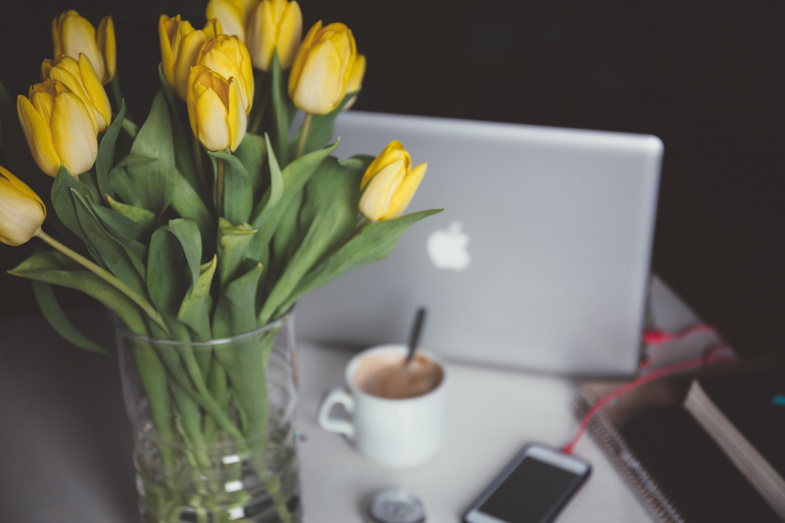 Un ordinateur, un café et un bouquet de fleurs
