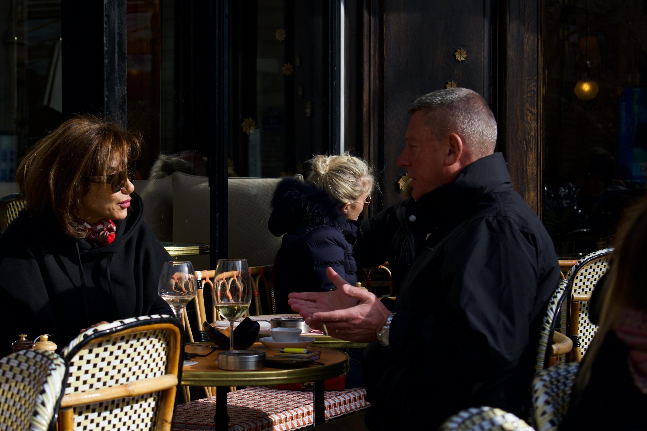 Deux personnes discutant à la terrasse d'un café parisien