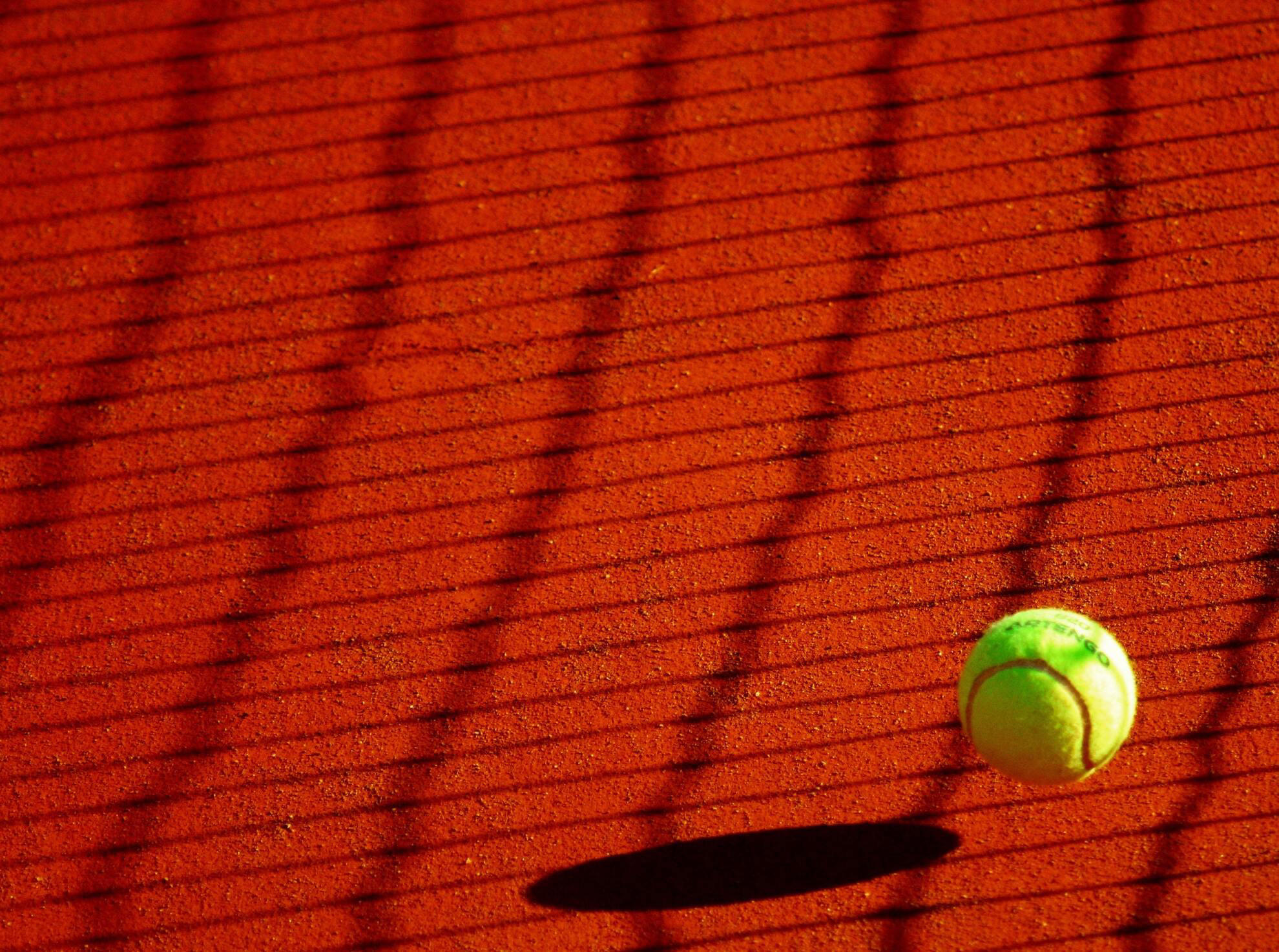 Balle de tennis rebondissant sur un court de tennis en terre battue. 