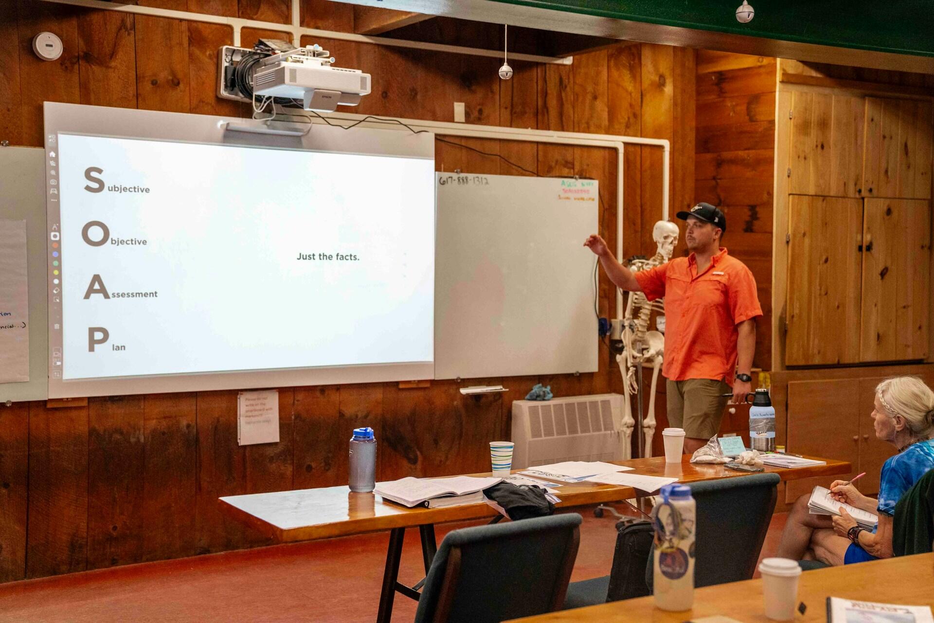 professeur devant la classe avec une présentation au tableau