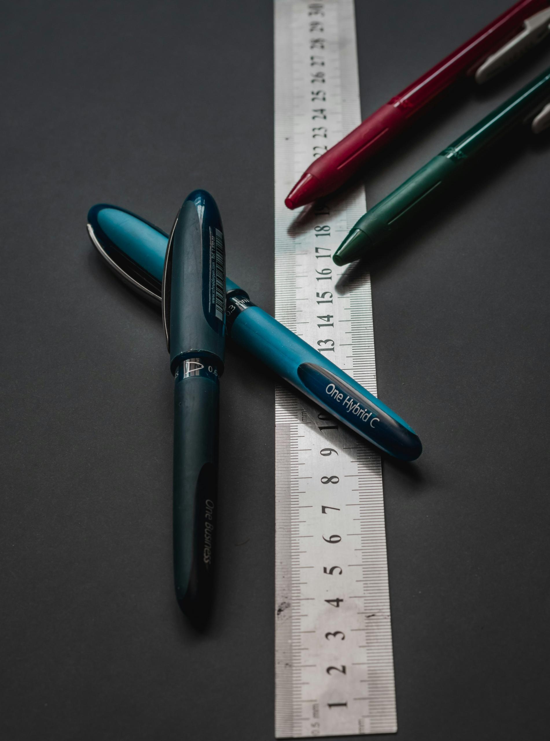 Des crayons posés sur une règle en métal.