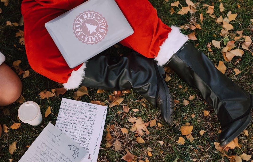 Père Noël assis dans l'herbe avec des lettres d'enfants. 