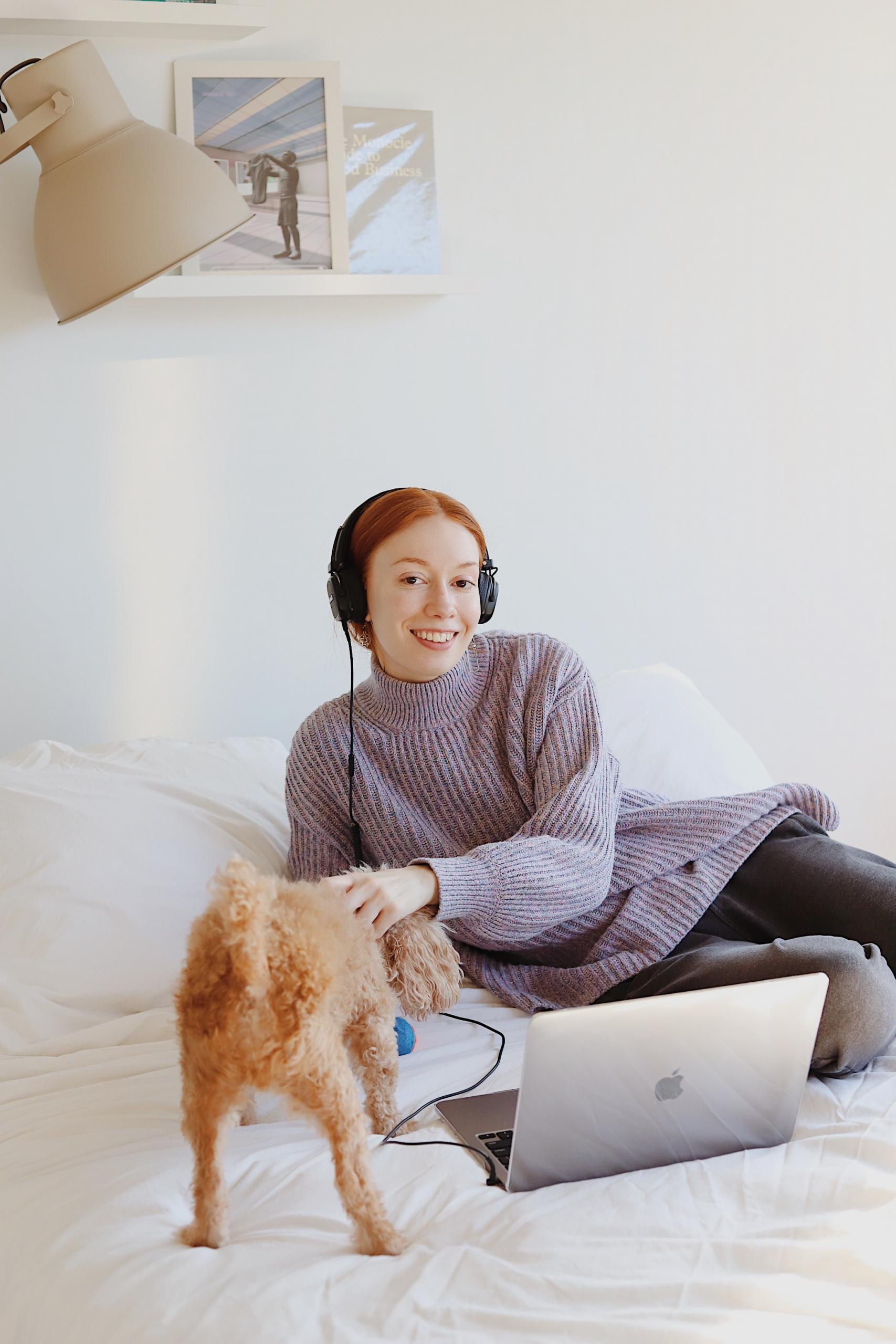 Une fille révise son bac en podcast sur son lit avec son chien.