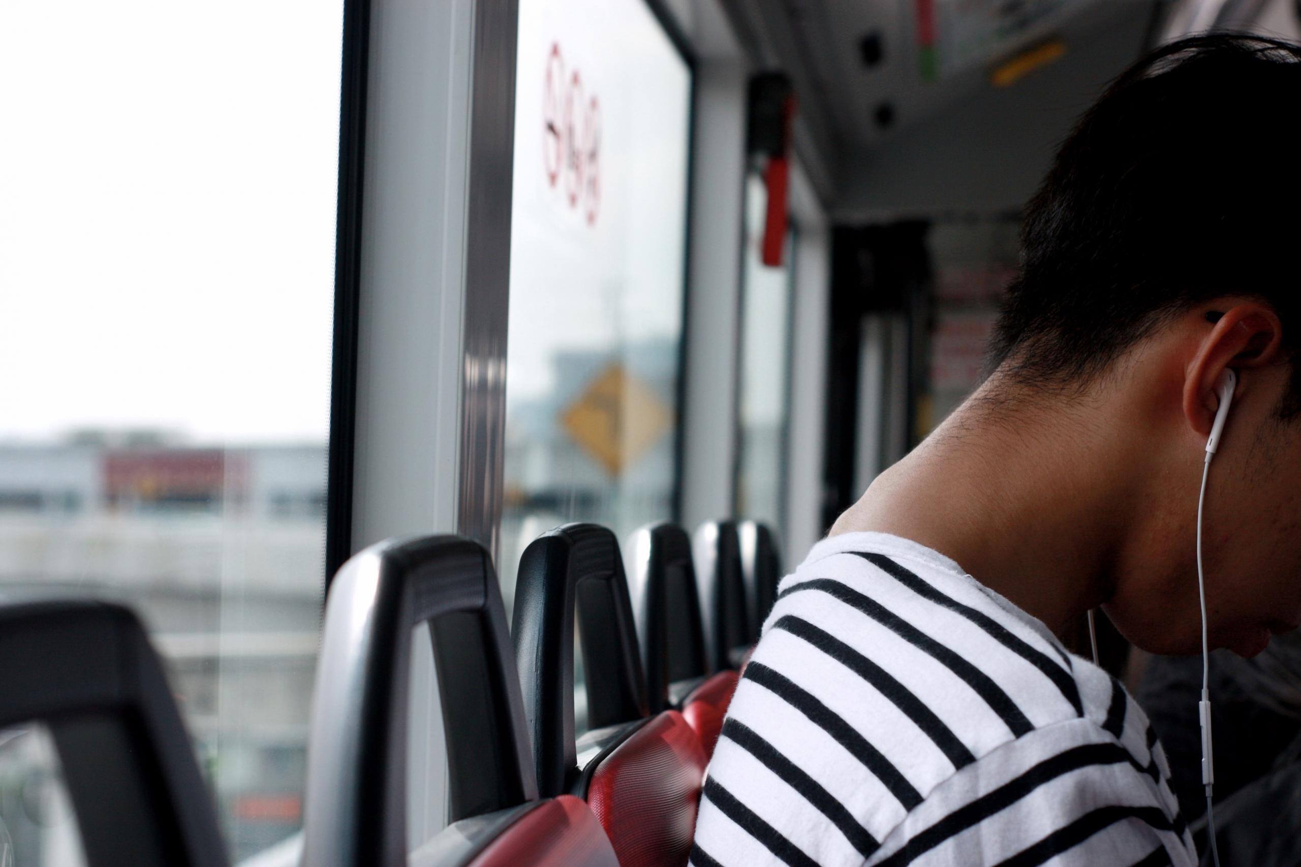Une femme assise dans le bus révise son bac avec des écouteurs.