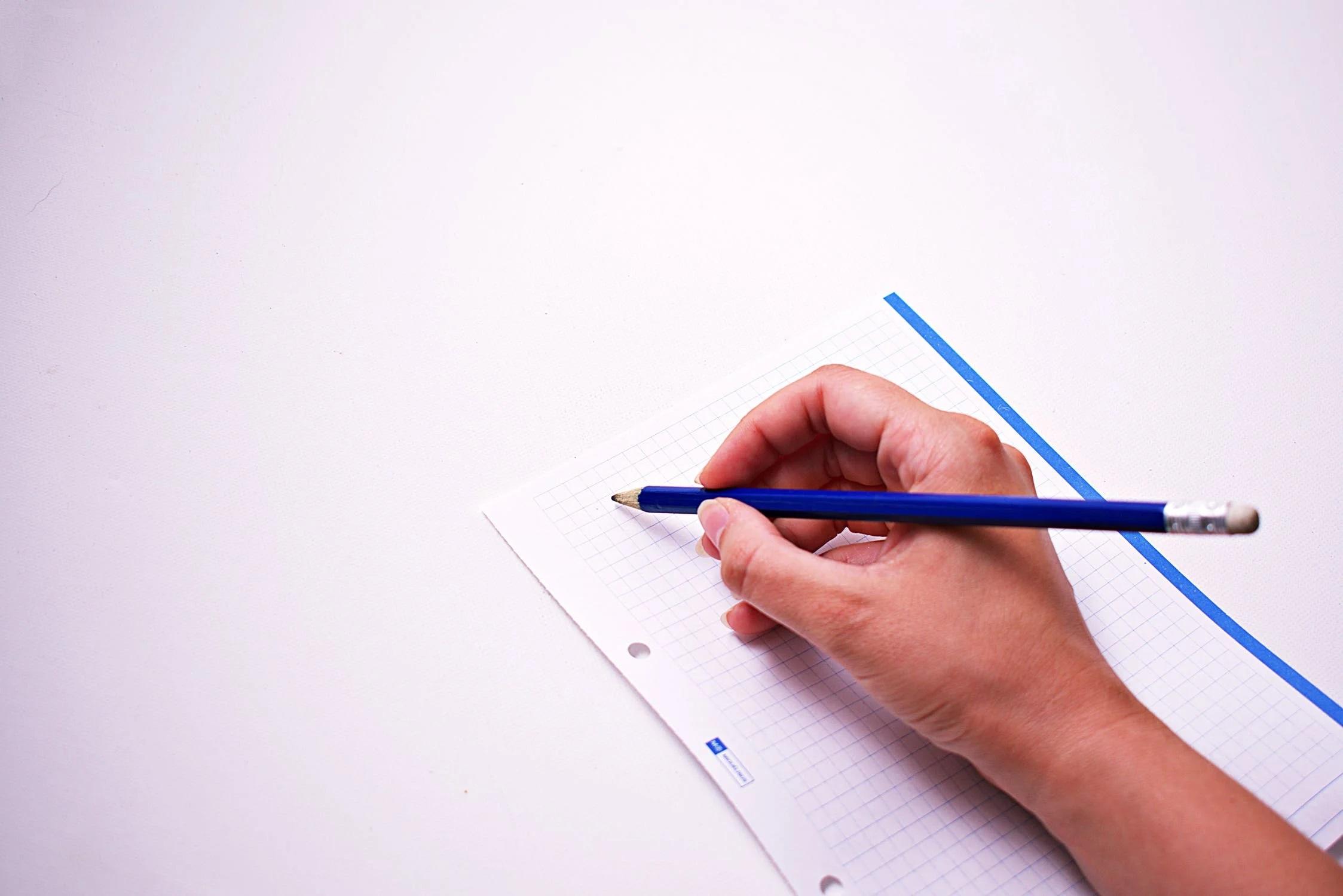 Une personne écrit sur un brouillon.