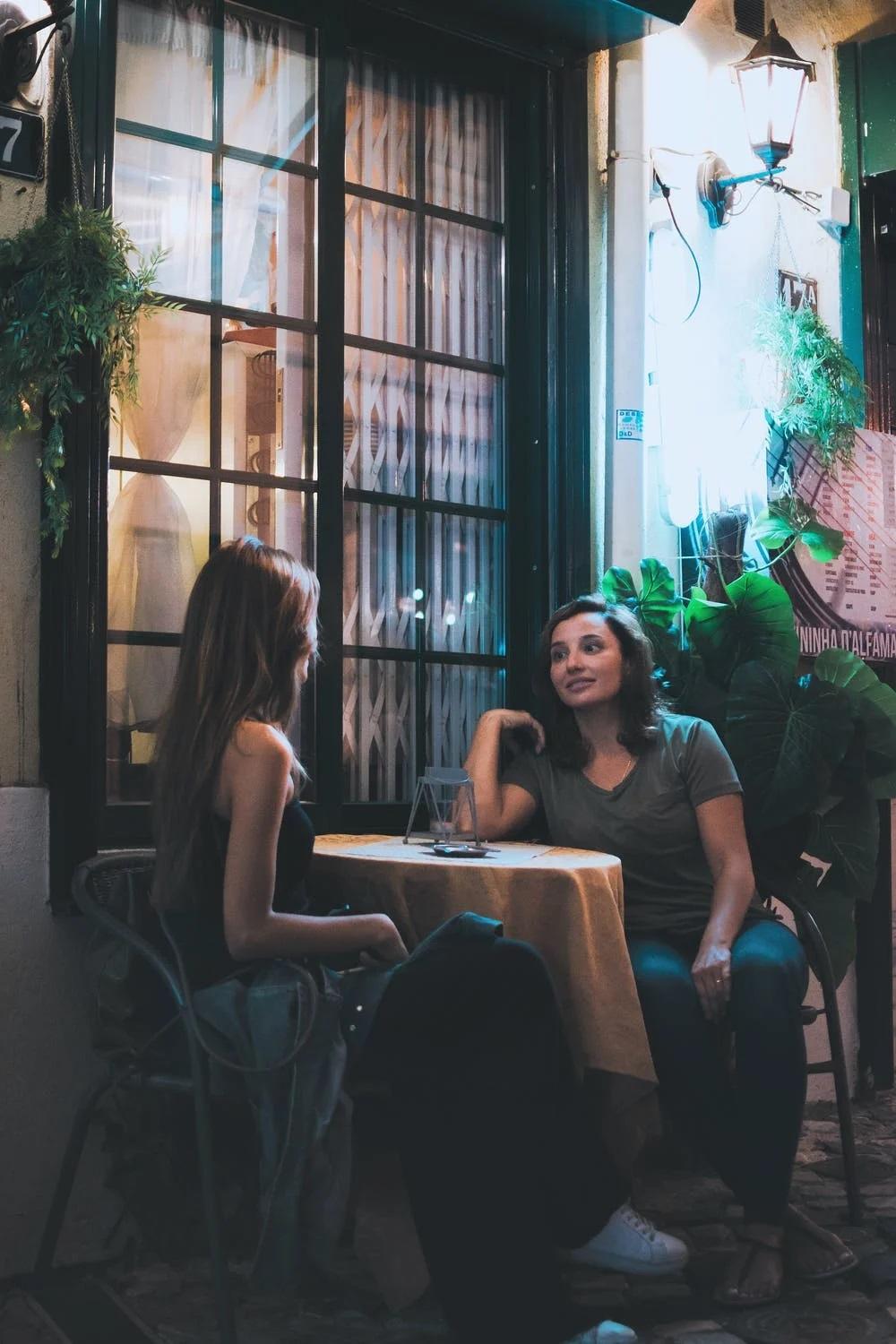 Deux femmes parlent français assises à une table.